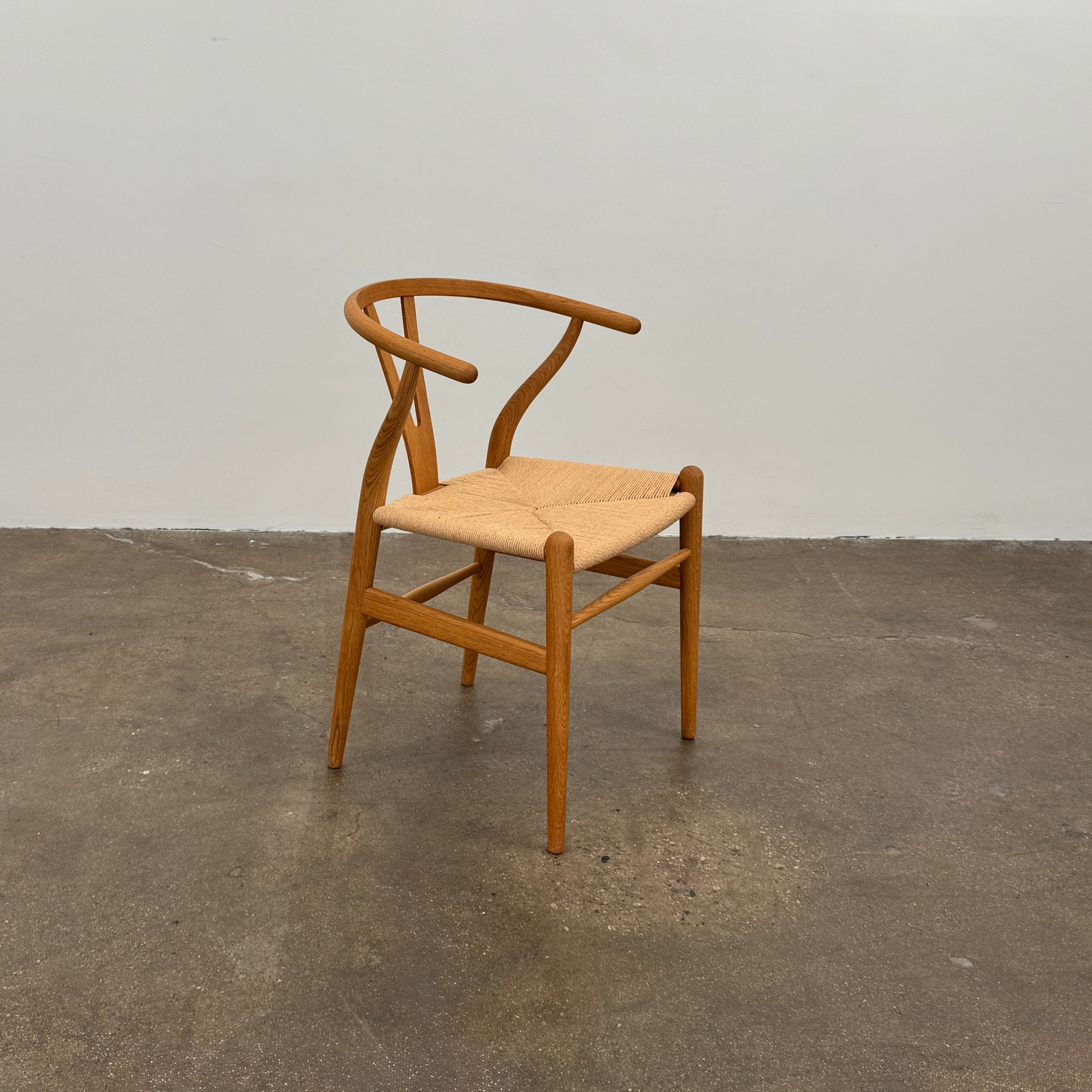 A set of two Carl Hansen & Søn Wishbone Dining Chairs by Carl Hansen & Son, featuring curved backrests and woven seats, are displayed side by side against a plain white background to highlight the renowned Danish craftsmanship inspired by Hans Wegner’s iconic design.