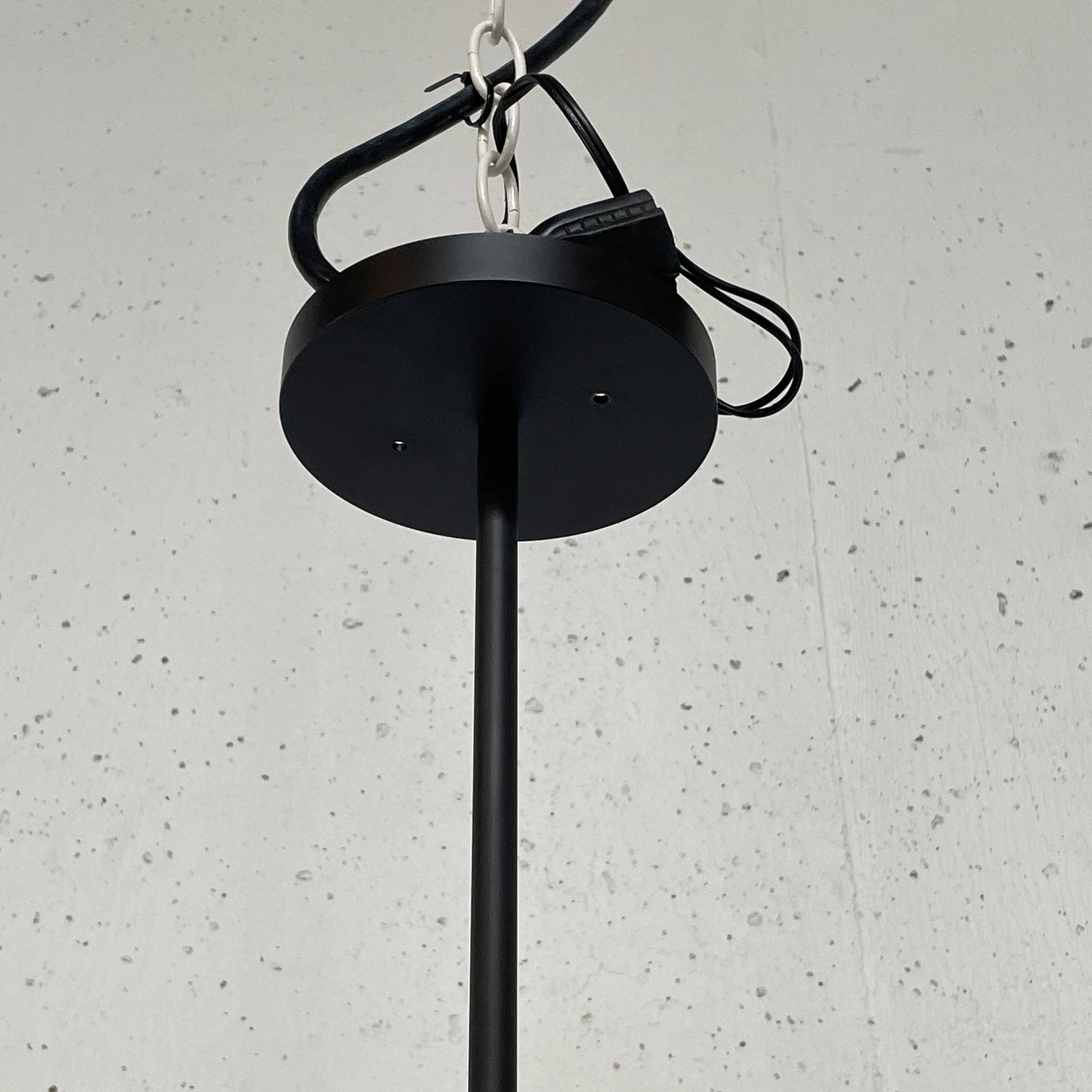 A unique functional art piece, this Alison Berger Word Pendant by Alison Berger showcases visible wires and mounting hardware against a white textured ceiling, reminiscent of Alison Berger's Word Pendant designs.