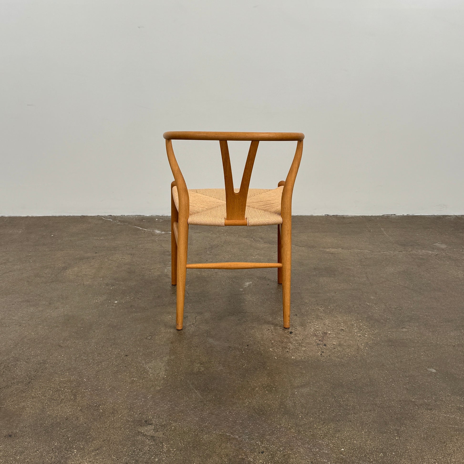 A set of two Carl Hansen & Søn Wishbone Dining Chairs by Carl Hansen & Son, featuring curved backrests and woven seats, are displayed side by side against a plain white background to highlight the renowned Danish craftsmanship inspired by Hans Wegner’s iconic design.