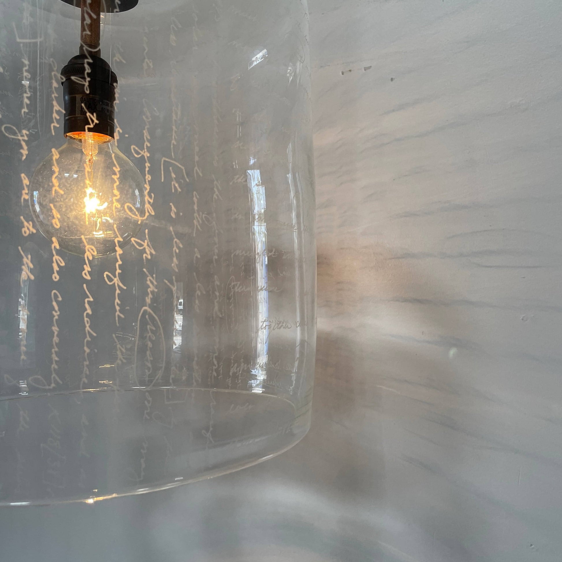 A unique functional art piece, this Alison Berger Word Pendant by Alison Berger showcases visible wires and mounting hardware against a white textured ceiling, reminiscent of Alison Berger's Word Pendant designs.