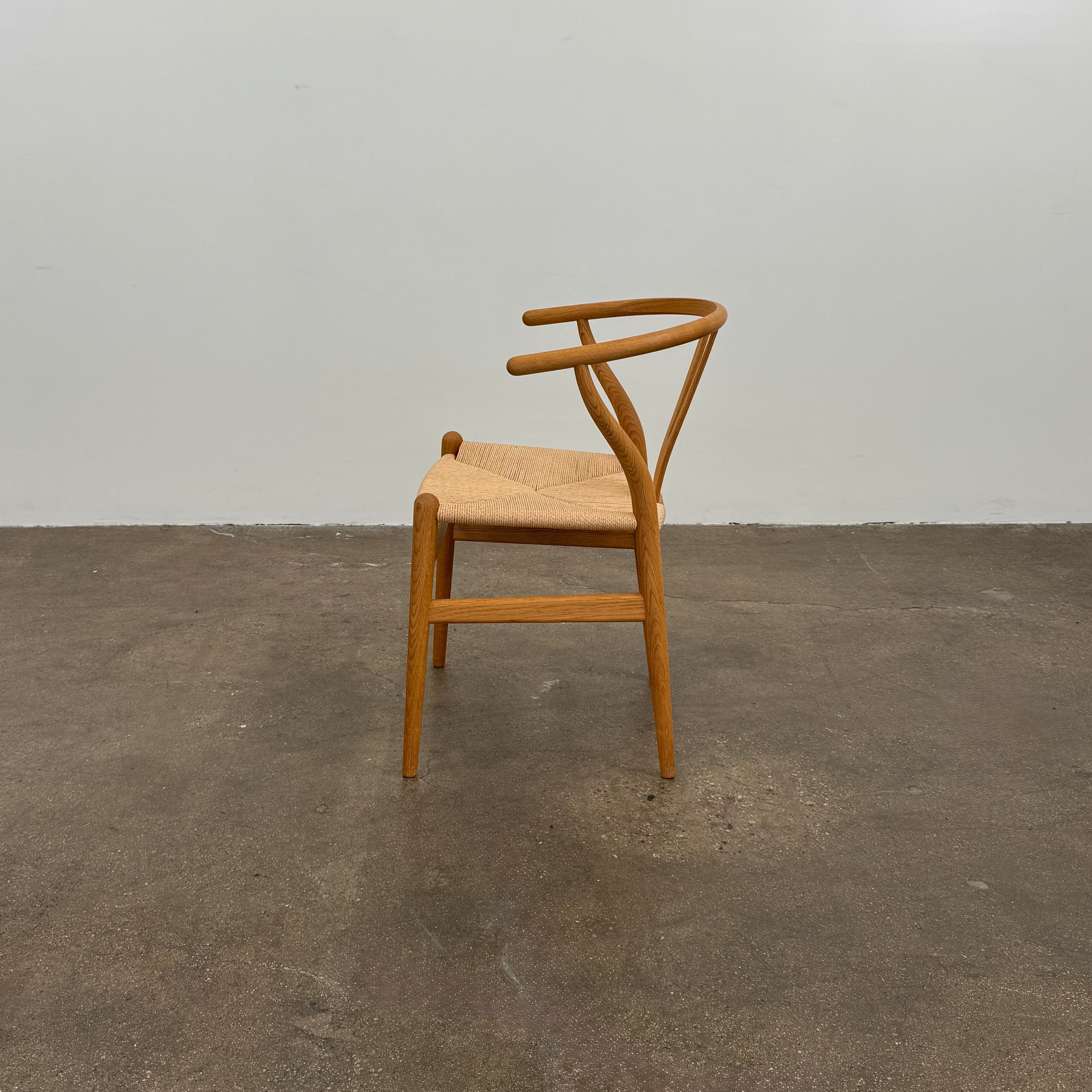 A set of two Carl Hansen & Søn Wishbone Dining Chairs by Carl Hansen & Son, featuring curved backrests and woven seats, are displayed side by side against a plain white background to highlight the renowned Danish craftsmanship inspired by Hans Wegner’s iconic design.