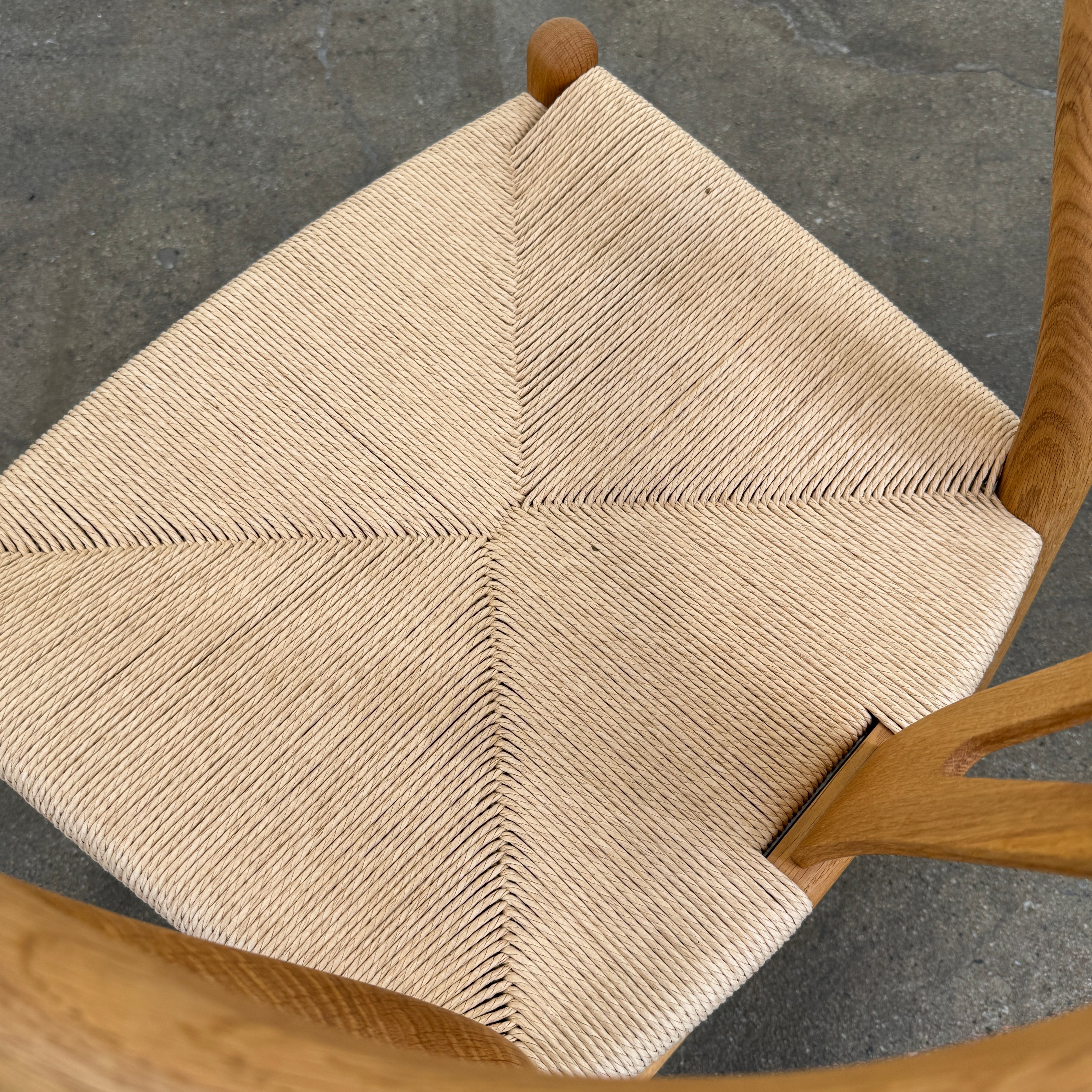 A set of two Carl Hansen & Søn Wishbone Dining Chairs by Carl Hansen & Son, featuring curved backrests and woven seats, are displayed side by side against a plain white background to highlight the renowned Danish craftsmanship inspired by Hans Wegner’s iconic design.