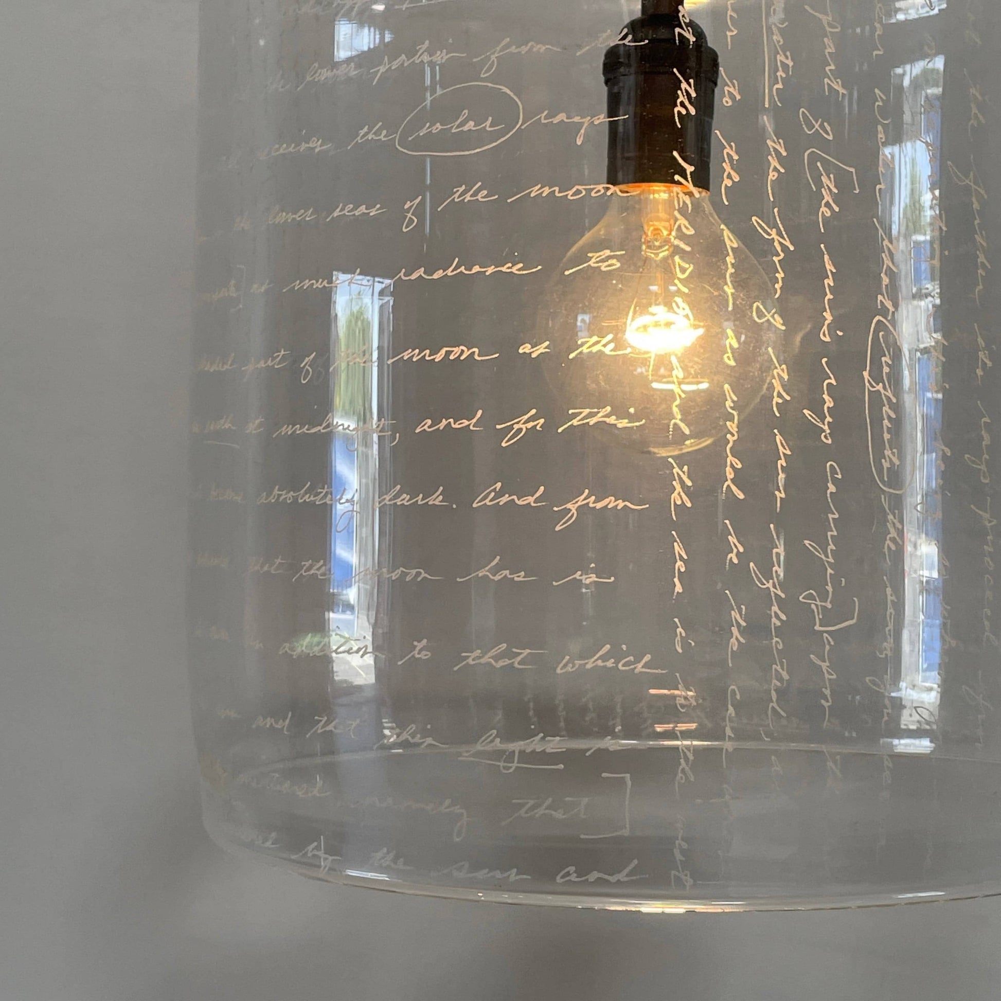 A unique functional art piece, this Alison Berger Word Pendant by Alison Berger showcases visible wires and mounting hardware against a white textured ceiling, reminiscent of Alison Berger's Word Pendant designs.