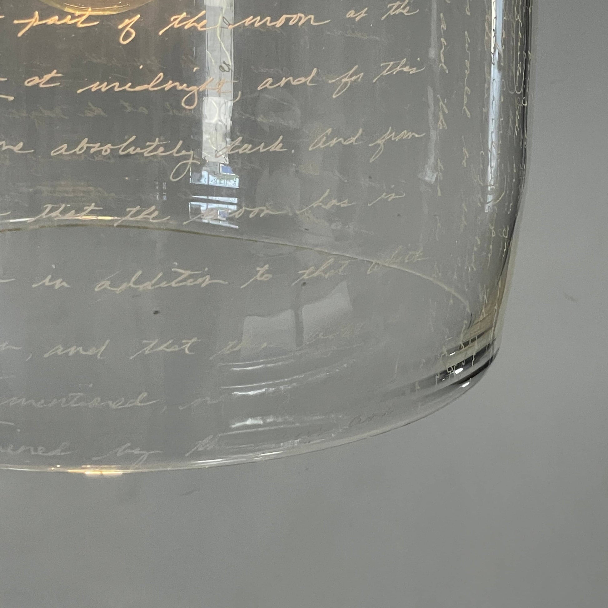 A unique functional art piece, this Alison Berger Word Pendant by Alison Berger showcases visible wires and mounting hardware against a white textured ceiling, reminiscent of Alison Berger's Word Pendant designs.