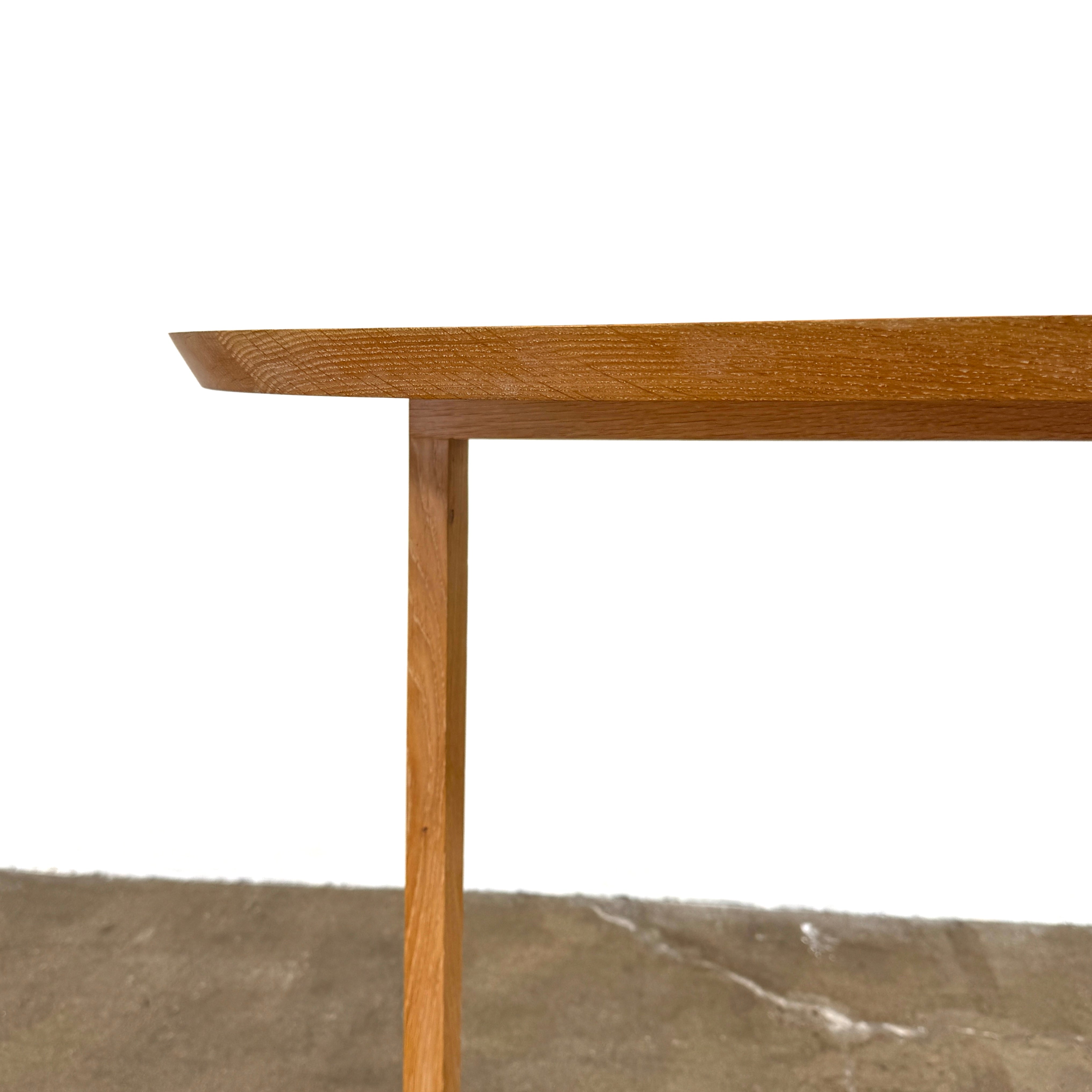 A De La Espada Trio Console Table 754CL by De La Espada stands against a white wall, showcasing modern woodworking with three vases, a beaded necklace, and a small stack of books arranged on its surface atop the concrete floor.