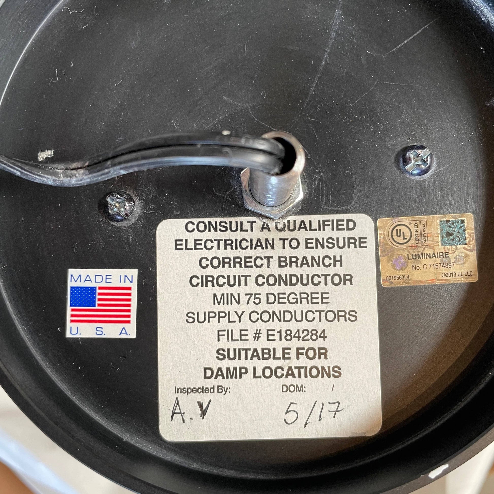 A unique functional art piece, this Alison Berger Word Pendant by Alison Berger showcases visible wires and mounting hardware against a white textured ceiling, reminiscent of Alison Berger's Word Pendant designs.