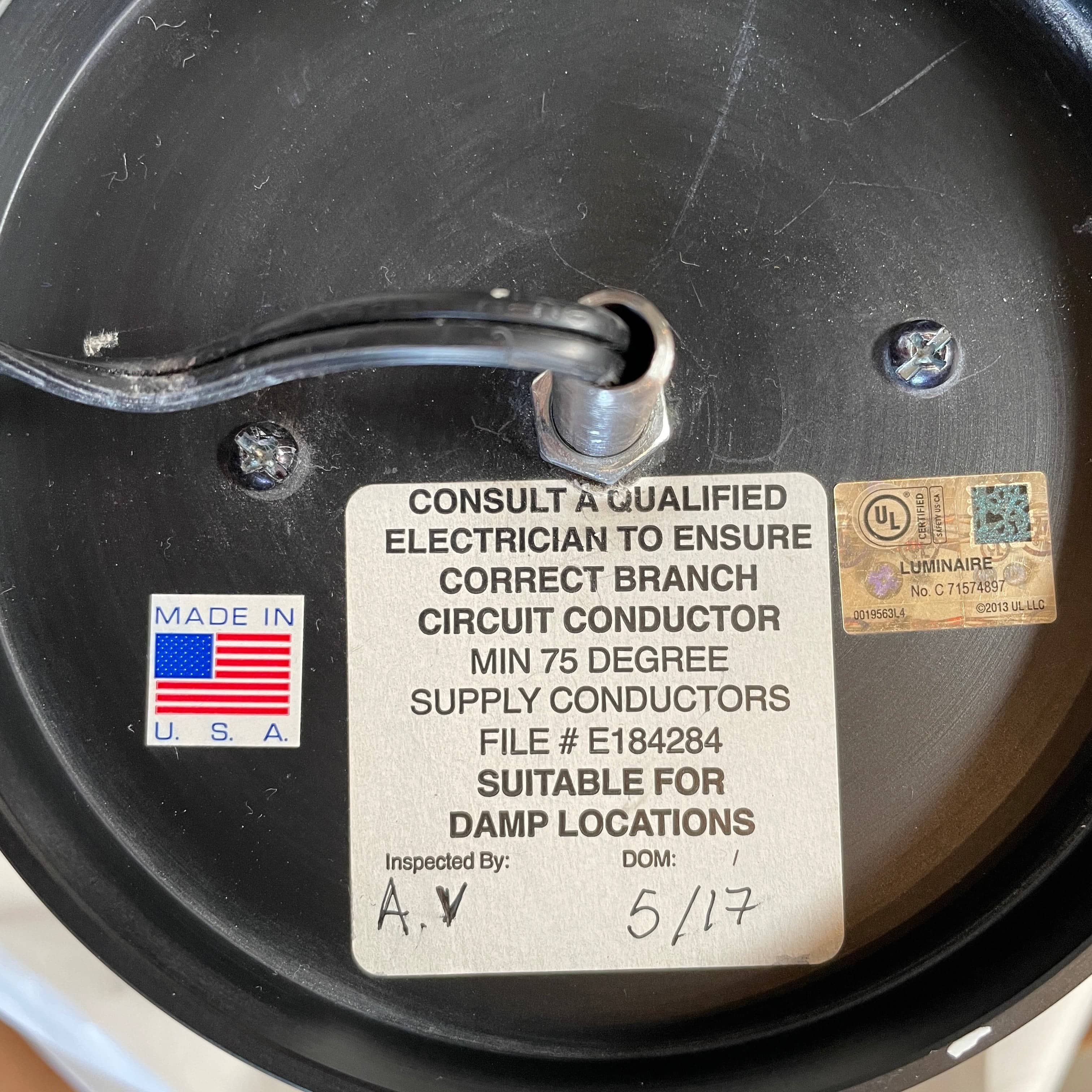 A unique functional art piece, this Alison Berger Word Pendant by Alison Berger showcases visible wires and mounting hardware against a white textured ceiling, reminiscent of Alison Berger's Word Pendant designs.