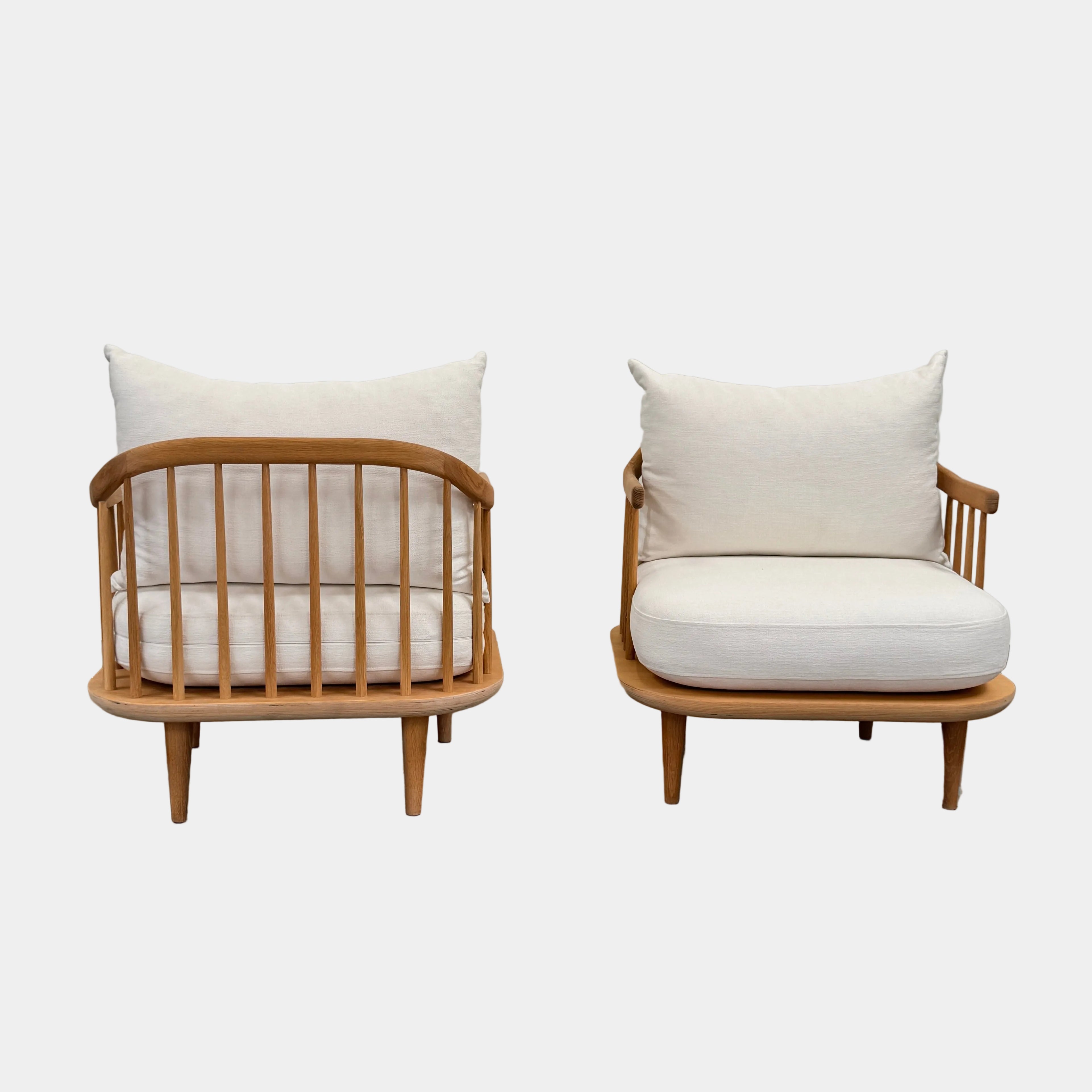Two &Tradition FLY Lounge Chairs by Modern Resale, featuring white cushions, are arranged side by side on a bare concrete floor against a plain white wall, embodying Nordic minimalism for a refined modern interior.