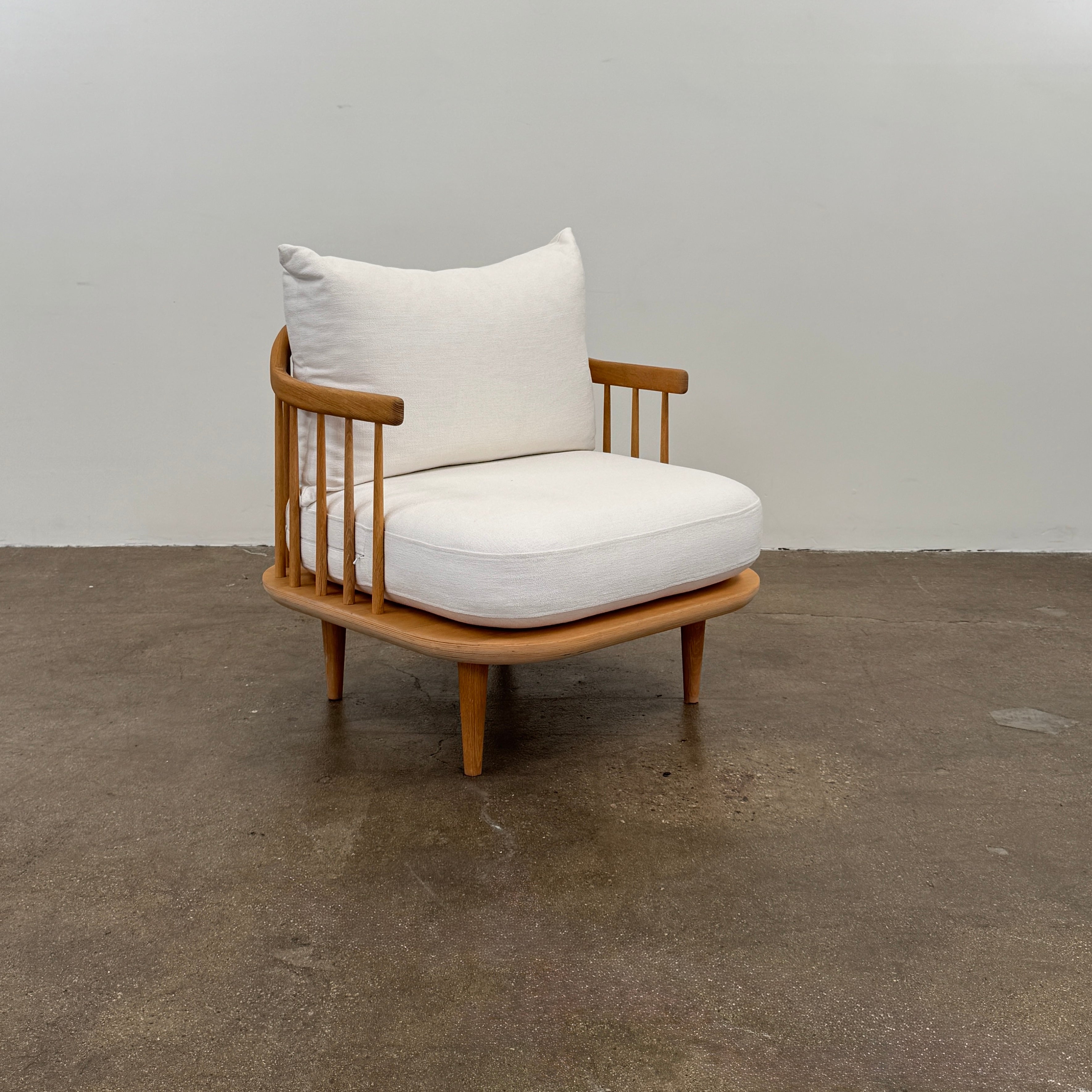 Two &Tradition FLY Lounge Chairs by Modern Resale, featuring white cushions, are arranged side by side on a bare concrete floor against a plain white wall, embodying Nordic minimalism for a refined modern interior.