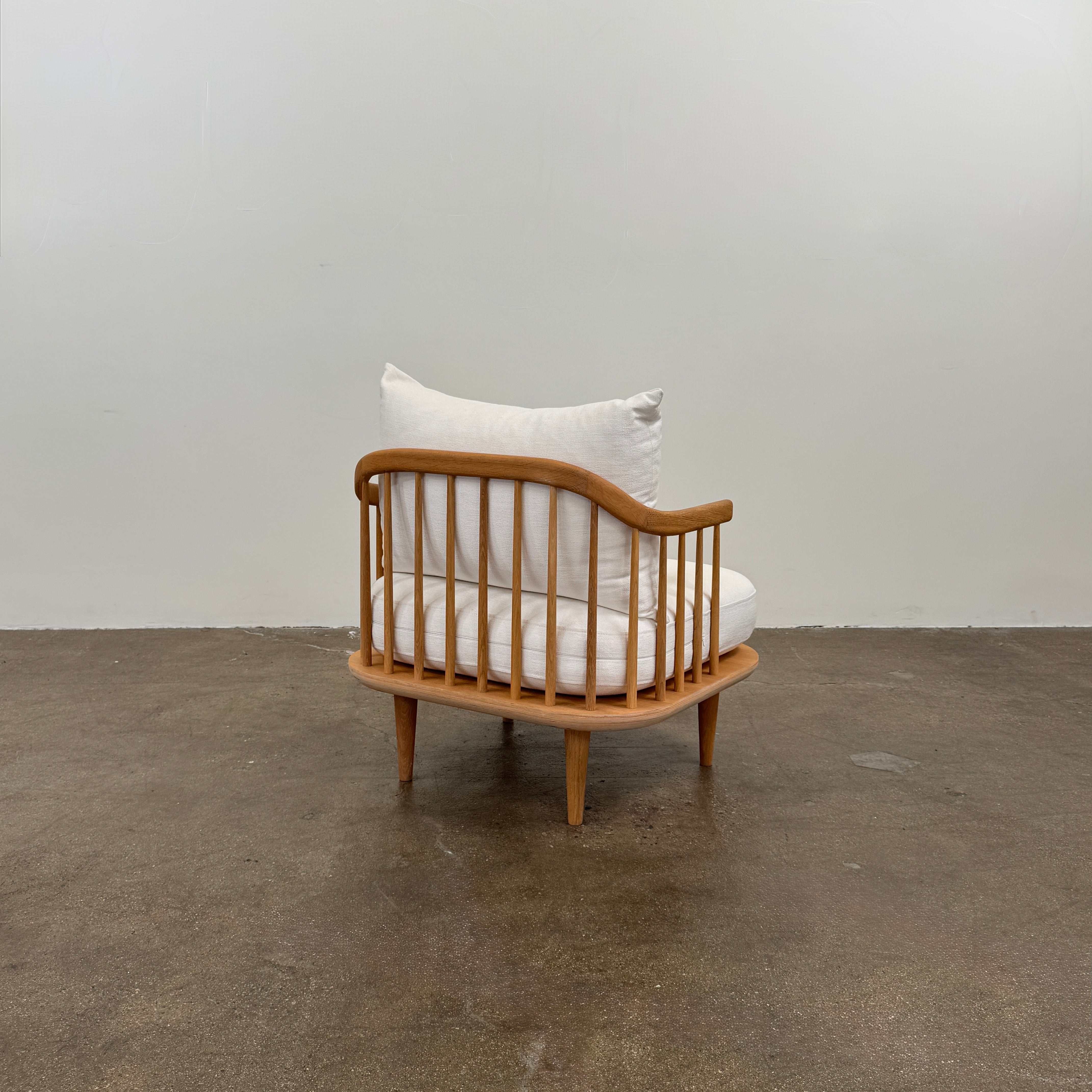 Two &Tradition FLY Lounge Chairs by Modern Resale, featuring white cushions, are arranged side by side on a bare concrete floor against a plain white wall, embodying Nordic minimalism for a refined modern interior.