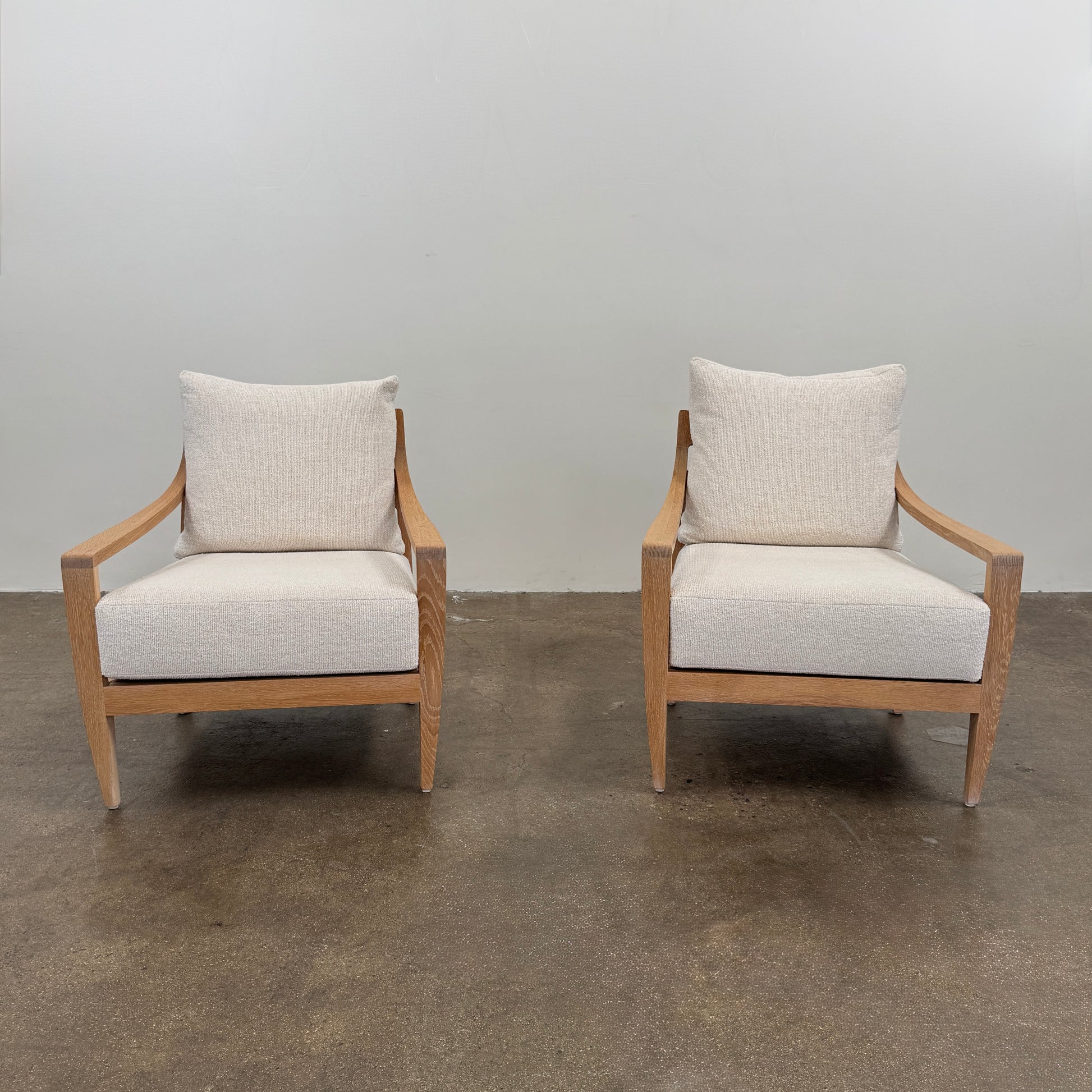 A De La Espada Low Lounge Chair 340 with light beige cushions is positioned on a polished concrete floor against a plain, light-colored wall.