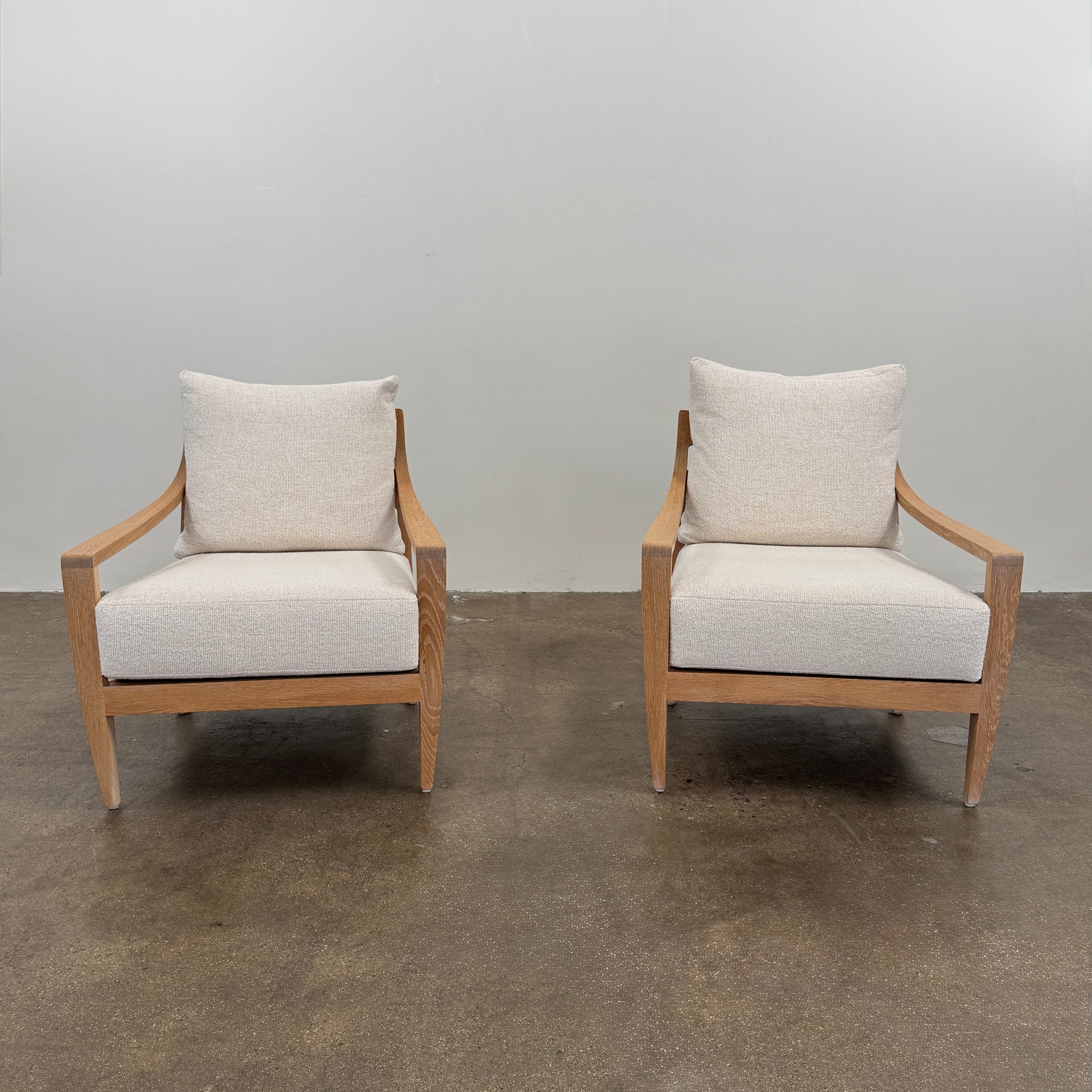 A De La Espada Low Lounge Chair 340 with light beige cushions is positioned on a polished concrete floor against a plain, light-colored wall.