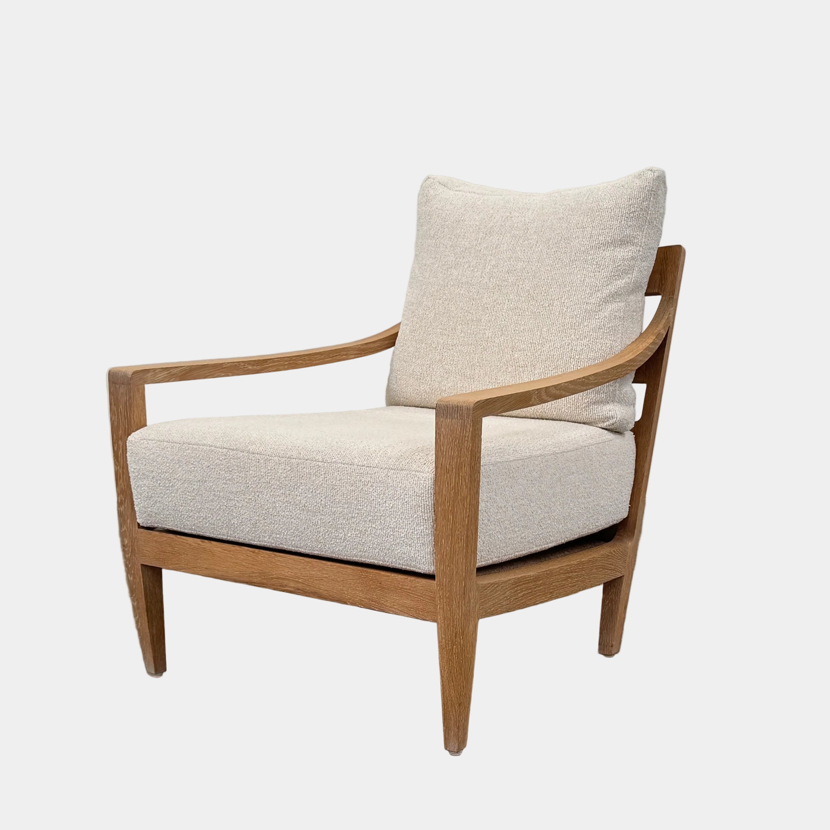 A De La Espada Low Lounge Chair 340 with light beige cushions is positioned on a polished concrete floor against a plain, light-colored wall.