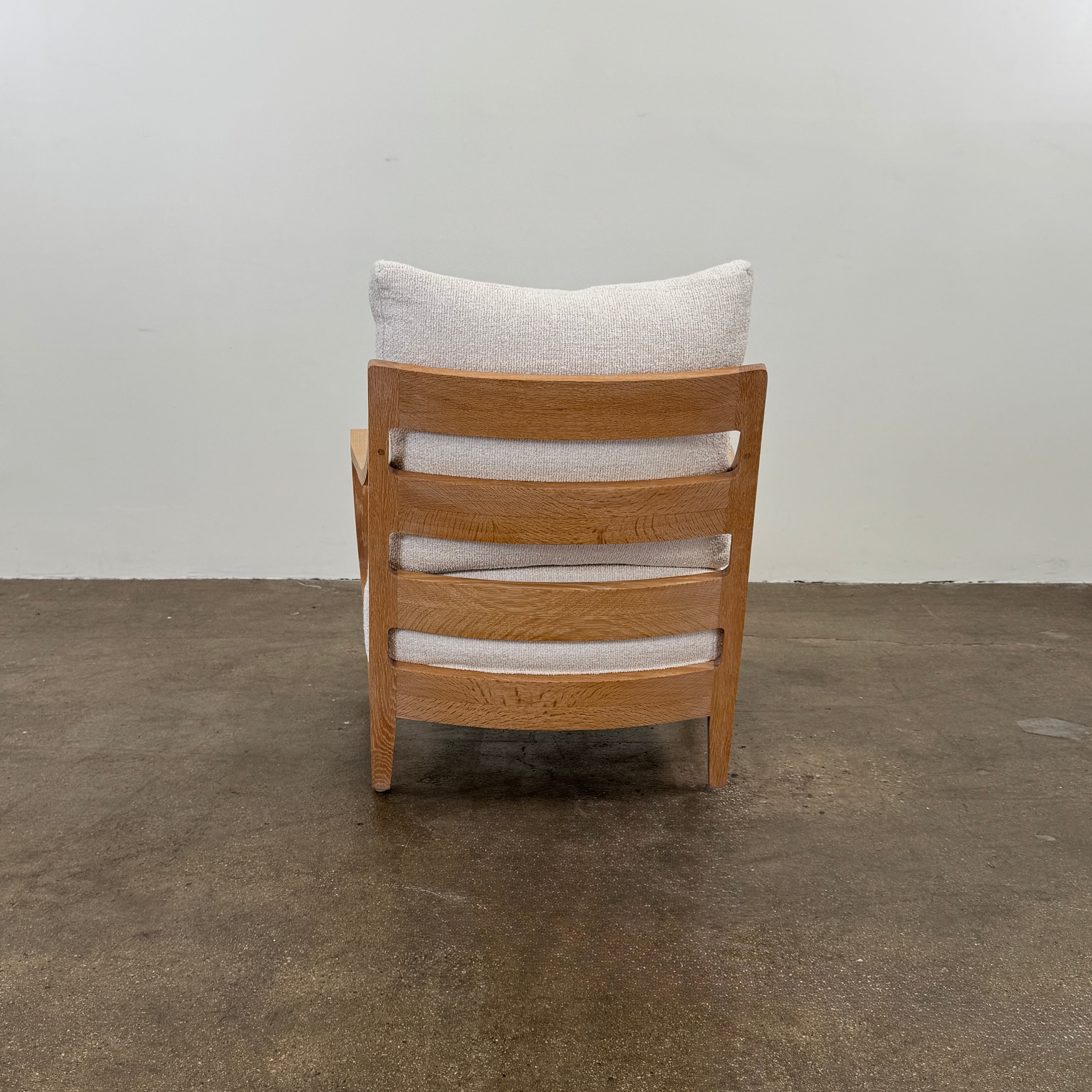 A De La Espada Low Lounge Chair 340 with light beige cushions is positioned on a polished concrete floor against a plain, light-colored wall.