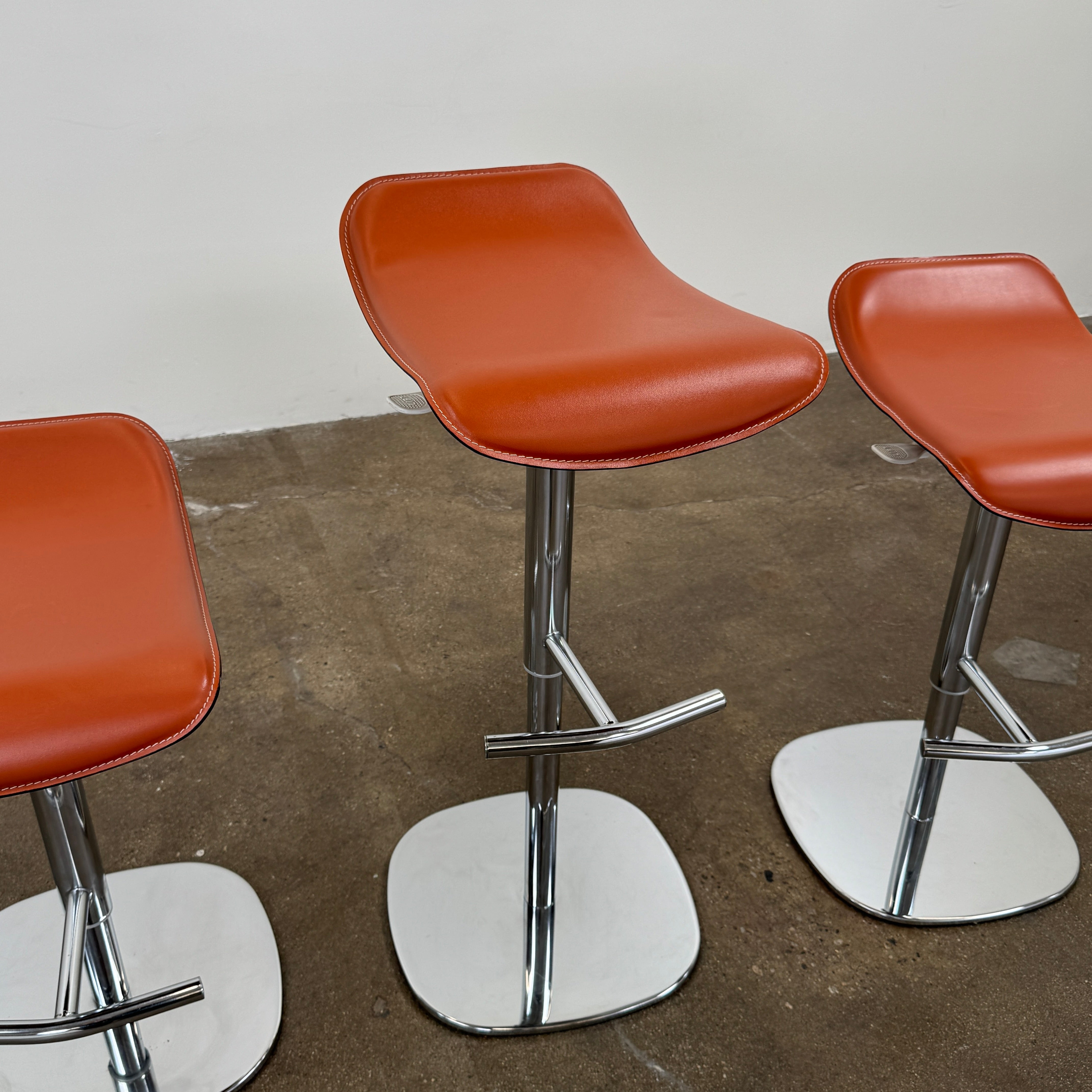 A set of three Giorgetti Ode Pneumatic Stools, featuring rich red-brown seats and sleek chrome bases, by luxury brand Giorgetti, are arranged in a row against a plain white background—exemplifying the refined elegance of Italian furniture design.