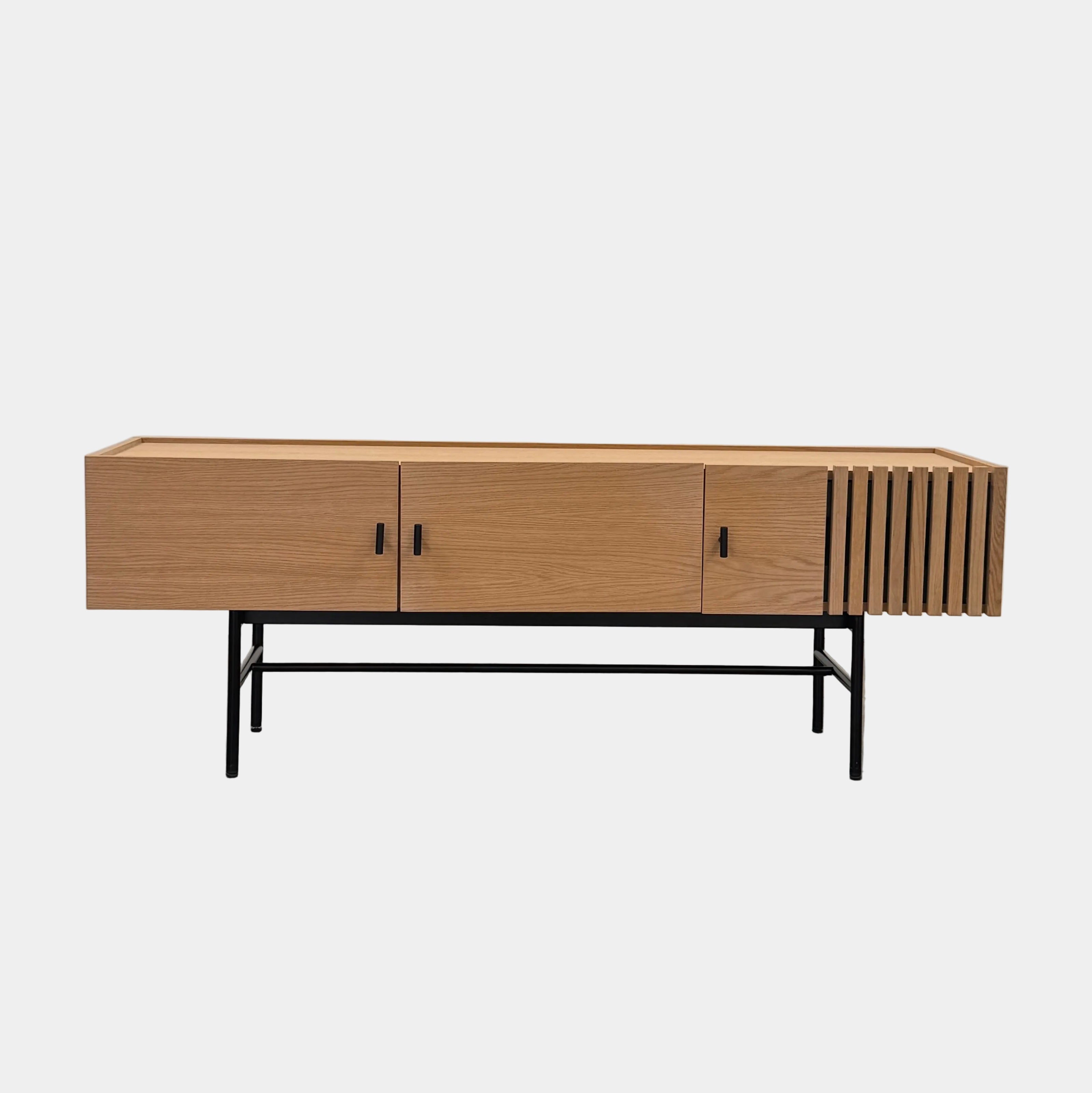 The Woud Array Low Sideboard White Pigmented Oak by Woud is a modern contemporary sideboard featuring three doors, sleek black metal legs, and elegant vertical slats on the right side. Crafted in white pigmented oak and presented against a plain white background, this piece brings stylish functionality to any interior.