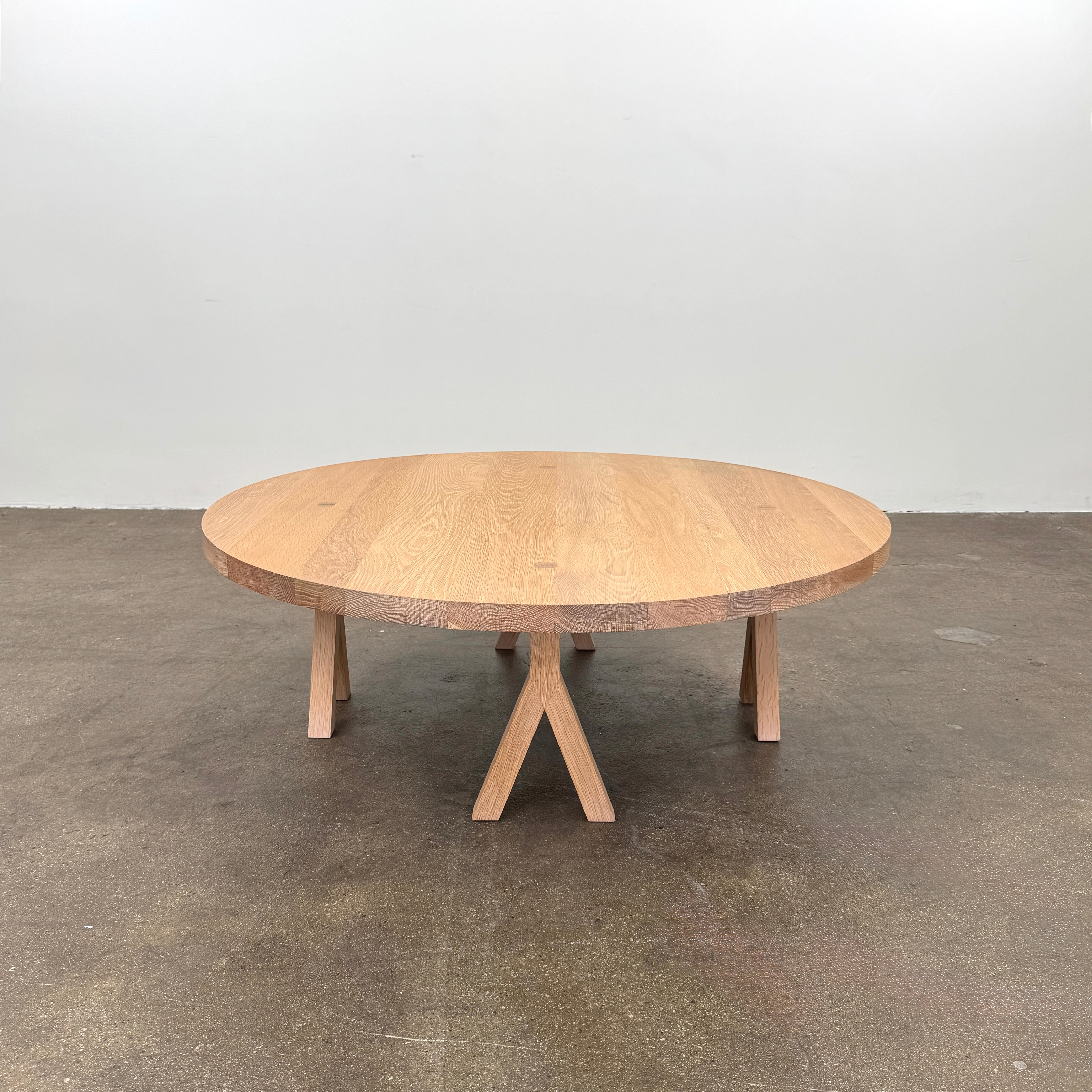The De La Espada Commune Coffee Table 772, crafted by De La Espada from solid oiled oak, features a smooth round top and four angled legs. Displayed against a plain white background, it is ideal for enhancing communal living spaces.