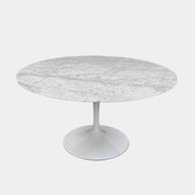 The Knoll Saarinen Table 54″ Round Arabescato Marble, designed by Knoll and inspired by the iconic Saarinen silhouette, features a single central pedestal base and is crafted from luxurious Arabescato marble. It is photographed against a plain white background.