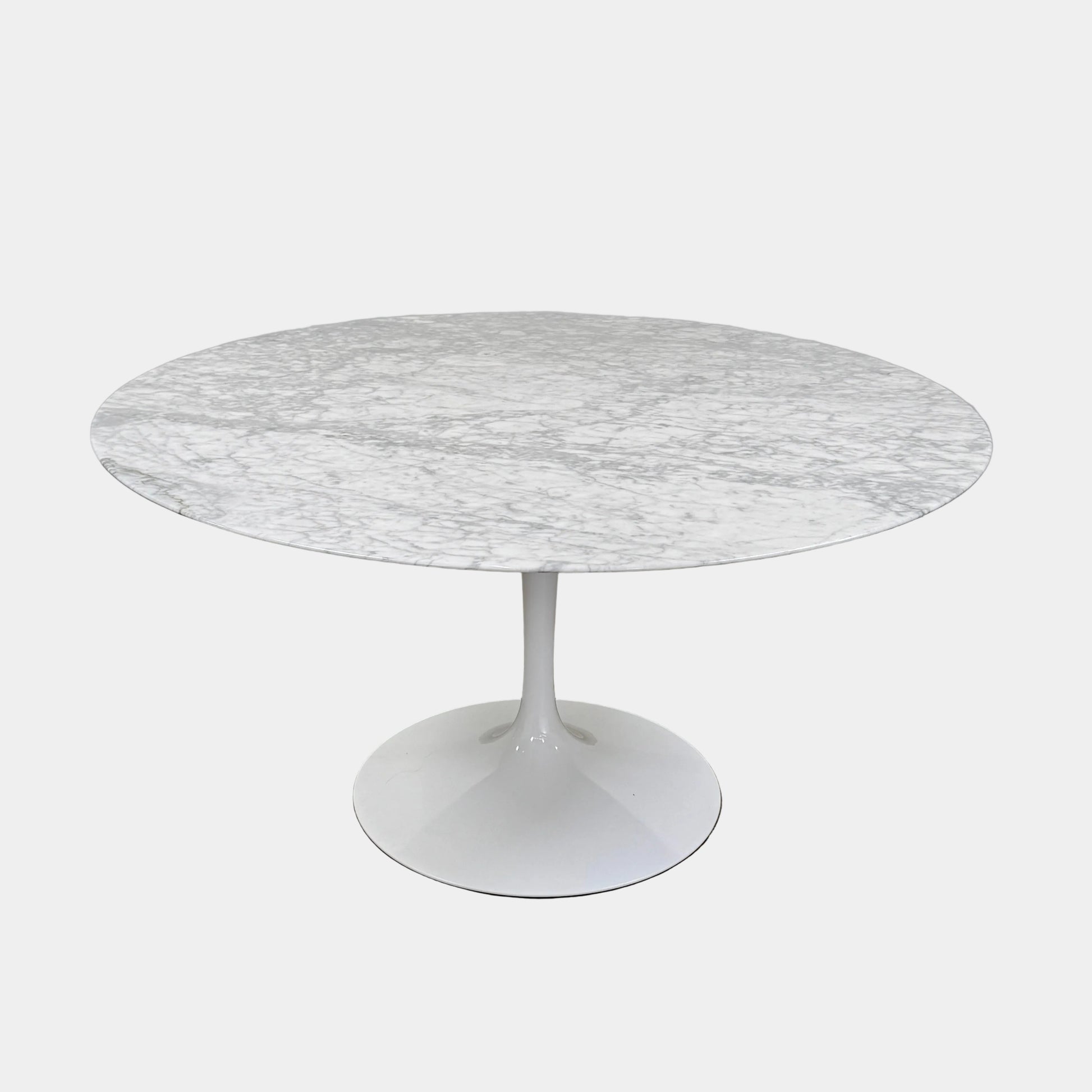 The Knoll Saarinen Table 54″ Round Arabescato Marble, designed by Knoll and inspired by the iconic Saarinen silhouette, features a single central pedestal base and is crafted from luxurious Arabescato marble. It is photographed against a plain white background.