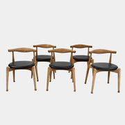 A set of five Carl Hansen & Son CH20 Elbow Chairs by Carl Hansen & Son, each with a curved wooden backrest and a round black seat cushion, are arranged in two rows against a plain white background.