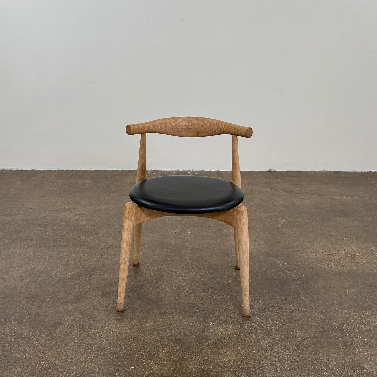 A set of five Carl Hansen & Son CH20 Elbow Chairs by Carl Hansen & Son, each with a curved wooden backrest and a round black seat cushion, are arranged in two rows against a plain white background.