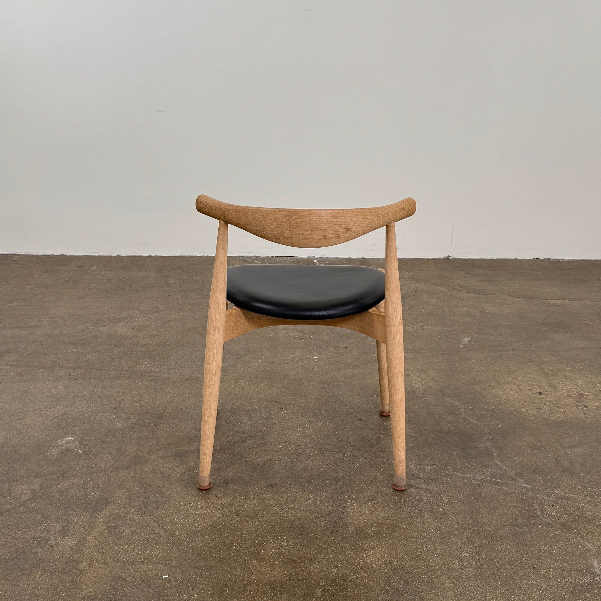 A set of five Carl Hansen & Son CH20 Elbow Chairs by Carl Hansen & Son, each with a curved wooden backrest and a round black seat cushion, are arranged in two rows against a plain white background.