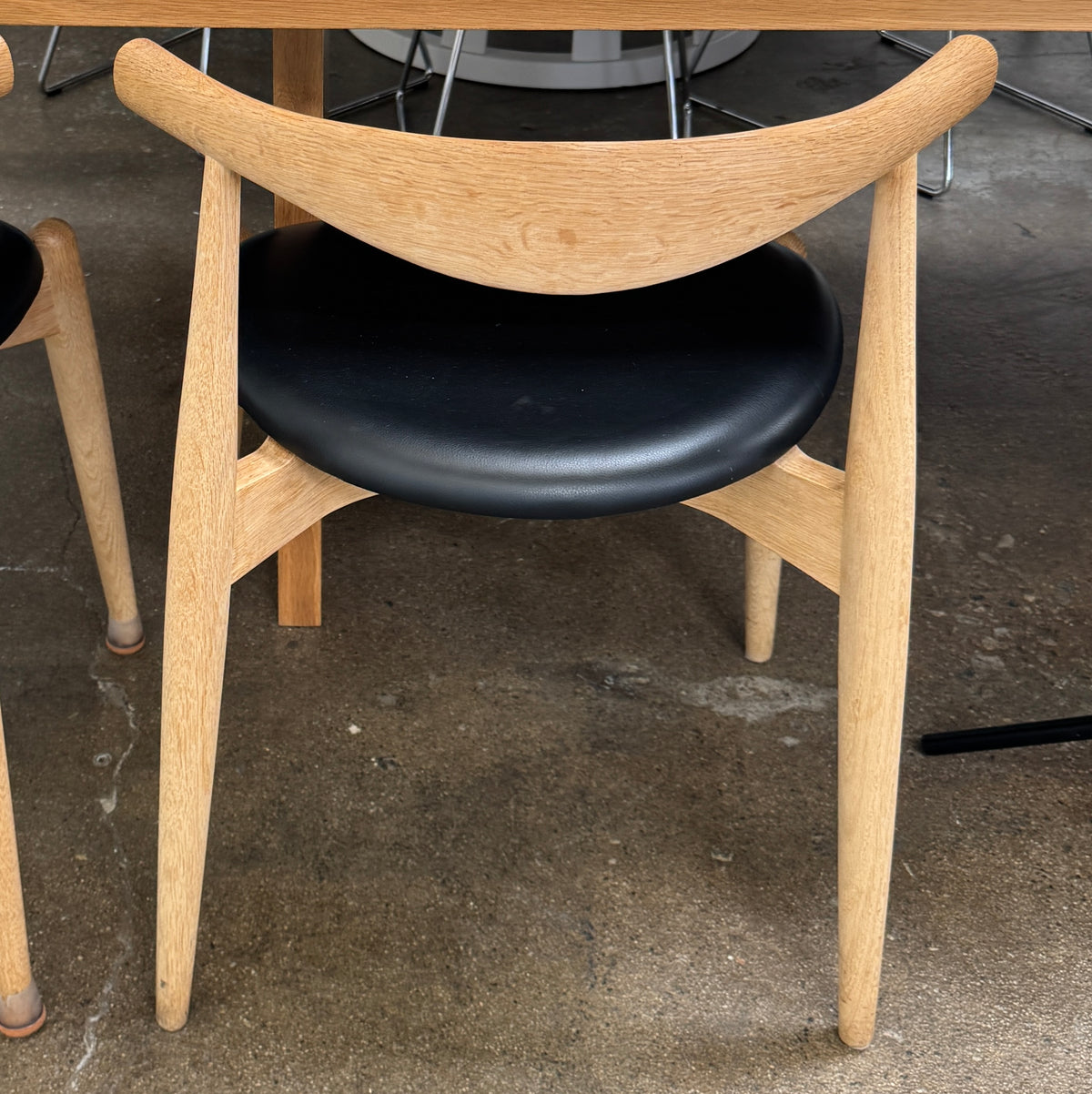 A set of five Carl Hansen & Son CH20 Elbow Chairs by Carl Hansen & Son, each with a curved wooden backrest and a round black seat cushion, are arranged in two rows against a plain white background.