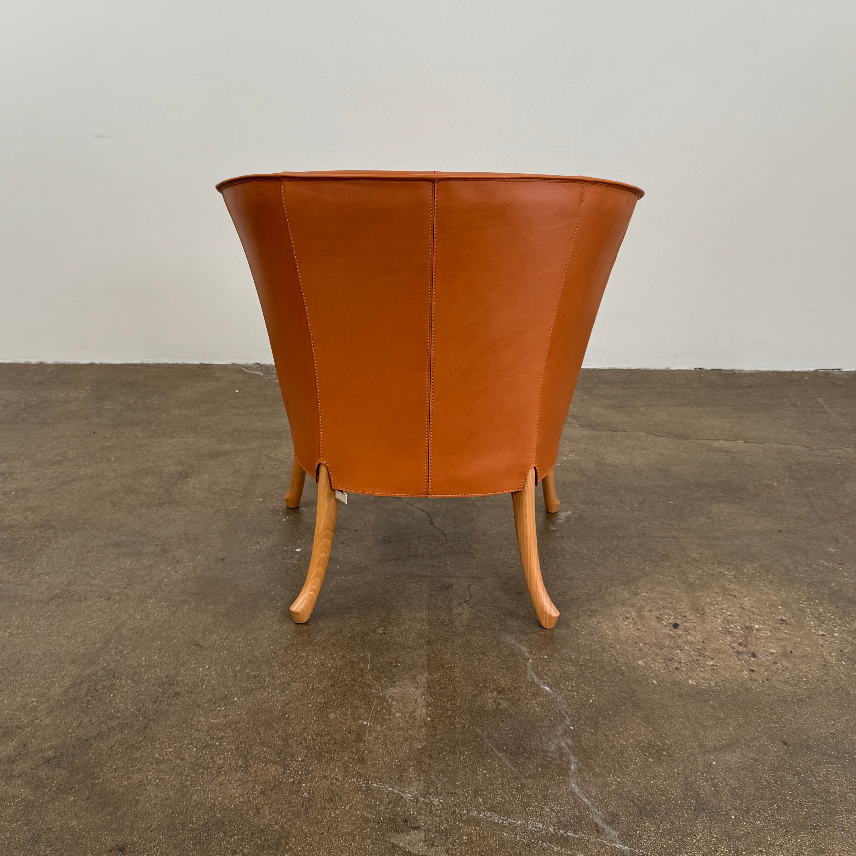 The Giorgetti “Progetti” Armchair by Giorgetti features a brown saddle leather seat, wooden legs, and Pau Ferro armrest accents, presented against a plain white background.