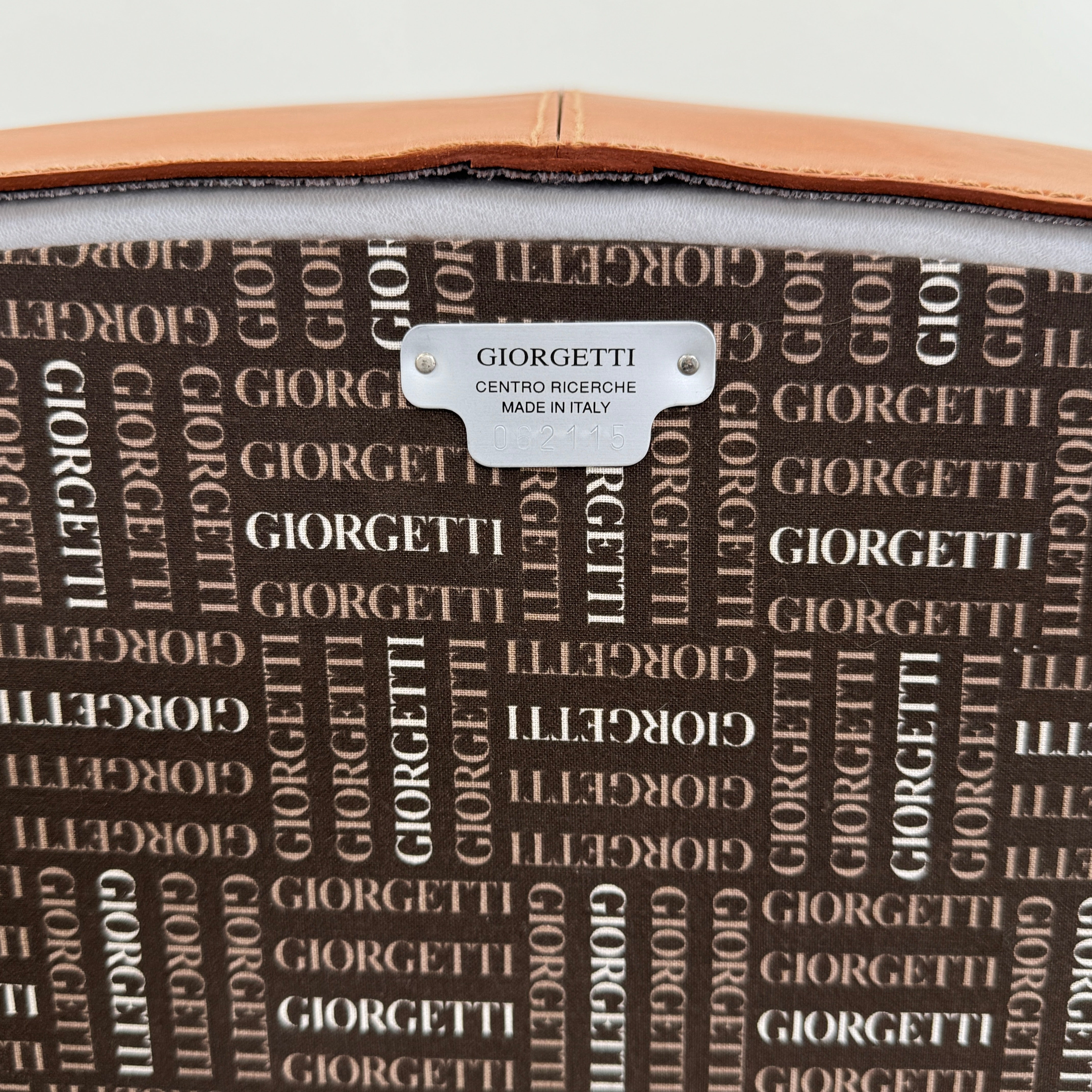 The Giorgetti “Progetti” Armchair by Giorgetti features a brown saddle leather seat, wooden legs, and Pau Ferro armrest accents, presented against a plain white background.