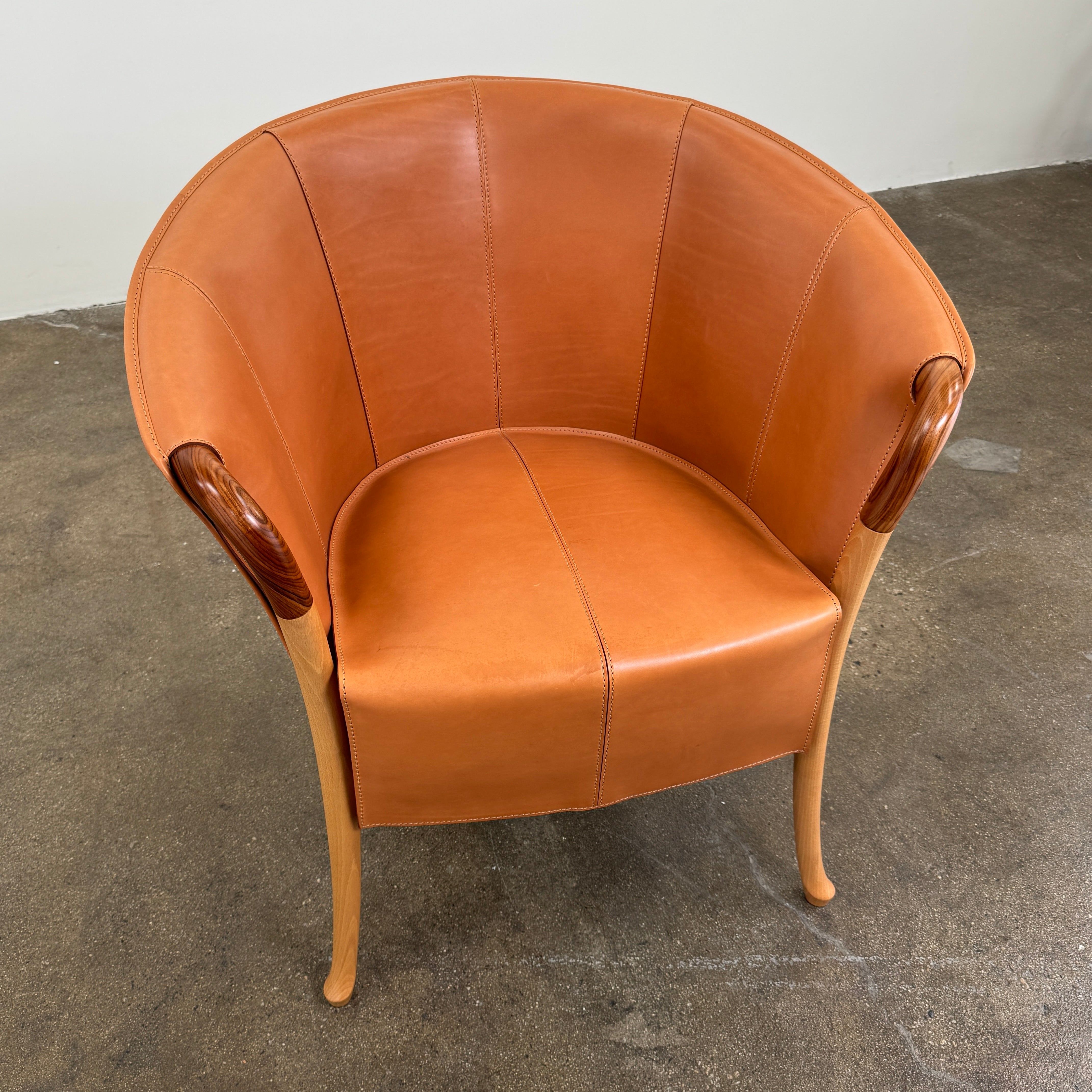 The Giorgetti “Progetti” Armchair by Giorgetti features a brown saddle leather seat, wooden legs, and Pau Ferro armrest accents, presented against a plain white background.