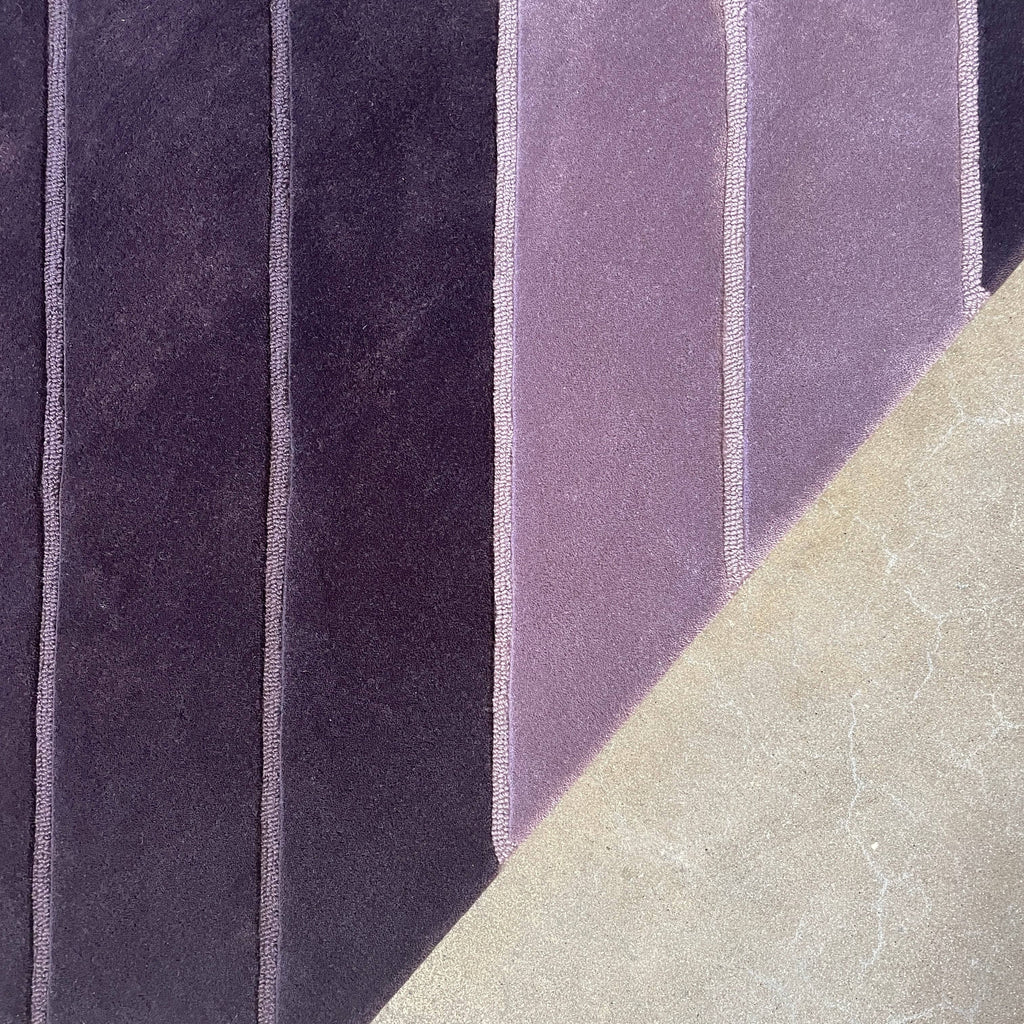 A Della Robbia Jay-V Custom Rug with purple and black stripes on it.