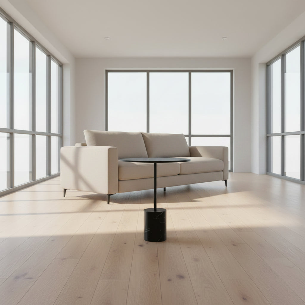 La Palma’s Jey Side Table features a minimalist black round top supported by a slim central column and anchored with a solid marble cylinder base, all showcased against a plain light background.