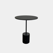La Palma’s Jey Side Table features a minimalist black round top supported by a slim central column and anchored with a solid marble cylinder base, all showcased against a plain light background.