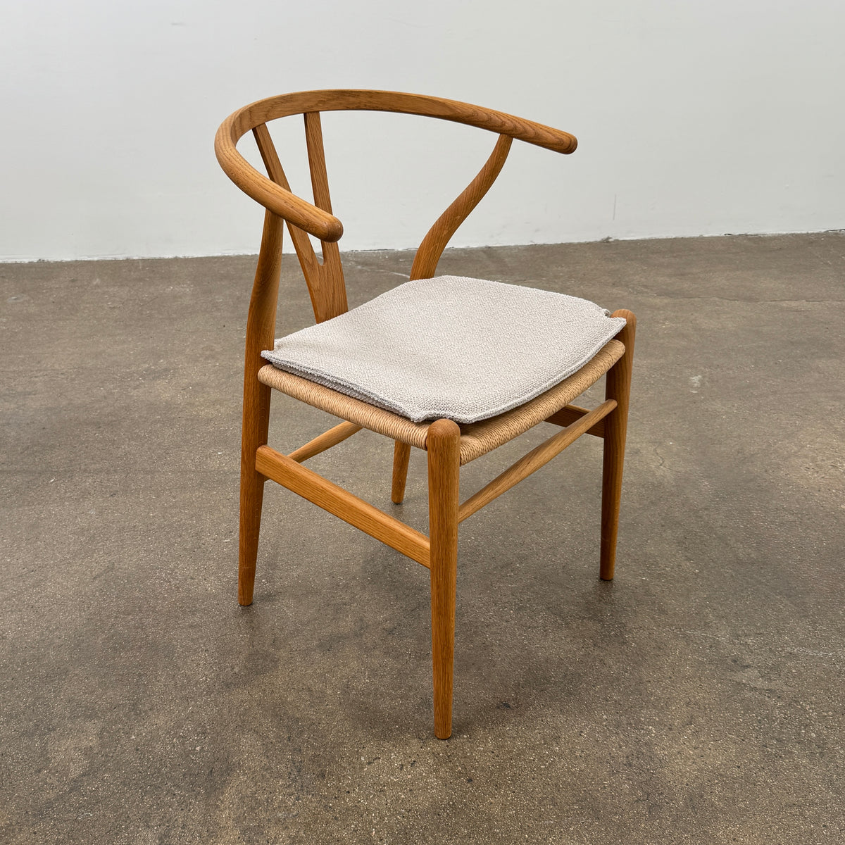 A set of two Carl Hansen & Søn Wishbone Dining Chairs by Carl Hansen & Son, featuring curved backrests and woven seats, are displayed side by side against a plain white background to highlight the renowned Danish craftsmanship inspired by Hans Wegner’s iconic design.