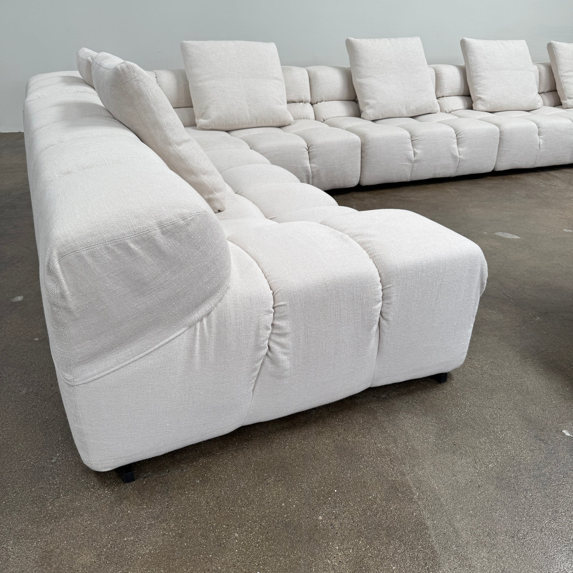 The B&B Italia 5 Piece Tufty Time Sectional by B&B Italia is a modular, cream-colored sectional sofa inspired by modern modular designs, featuring five labeled units—each with its own specific dimensions detailed in the accompanying chart below the image.
