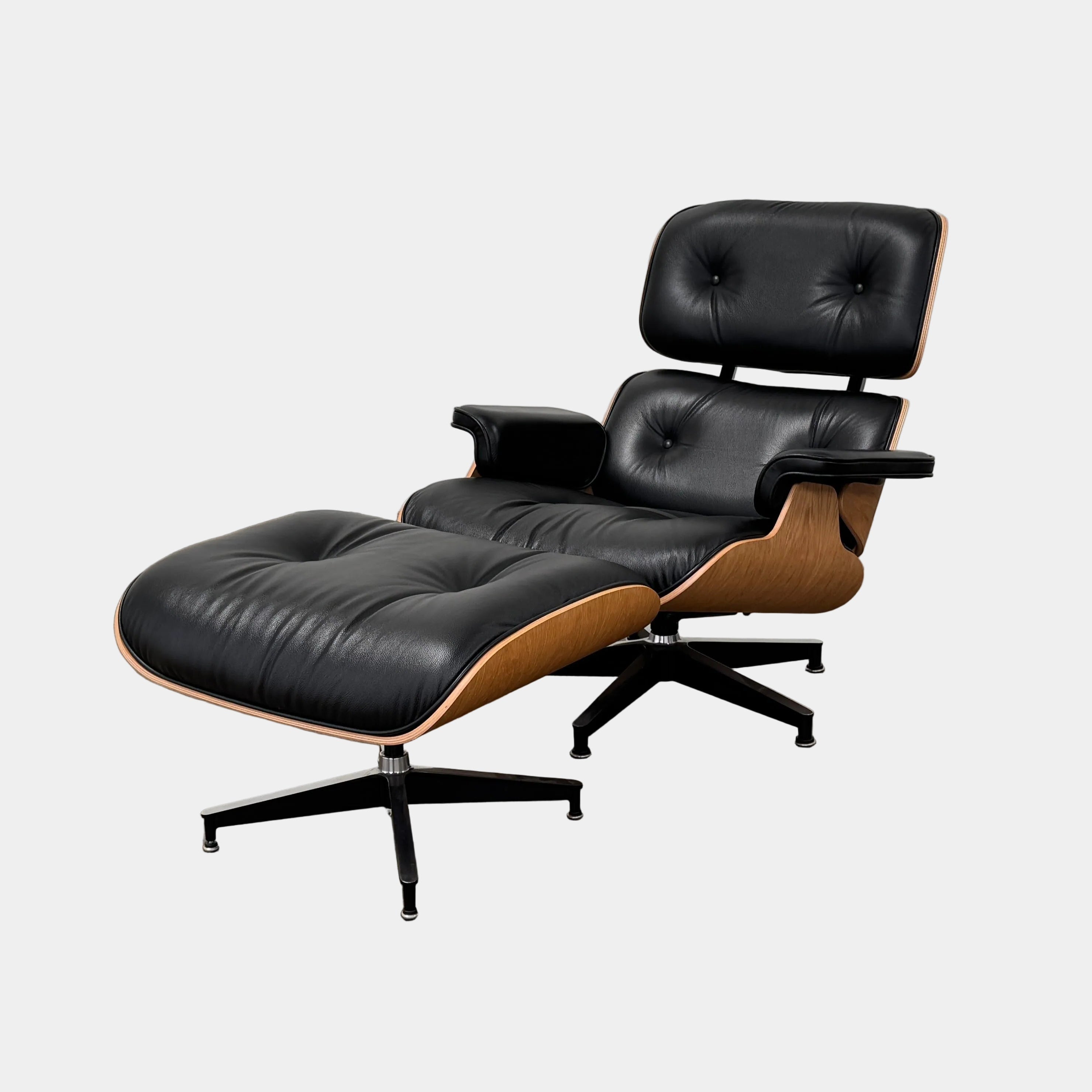 The Herman Miller Eames Lounge Chair & Ottoman (Copy) by Herman Miller, featuring black leather upholstery and modern design inspiration, is positioned on a brown concrete floor against a plain light-colored wall.