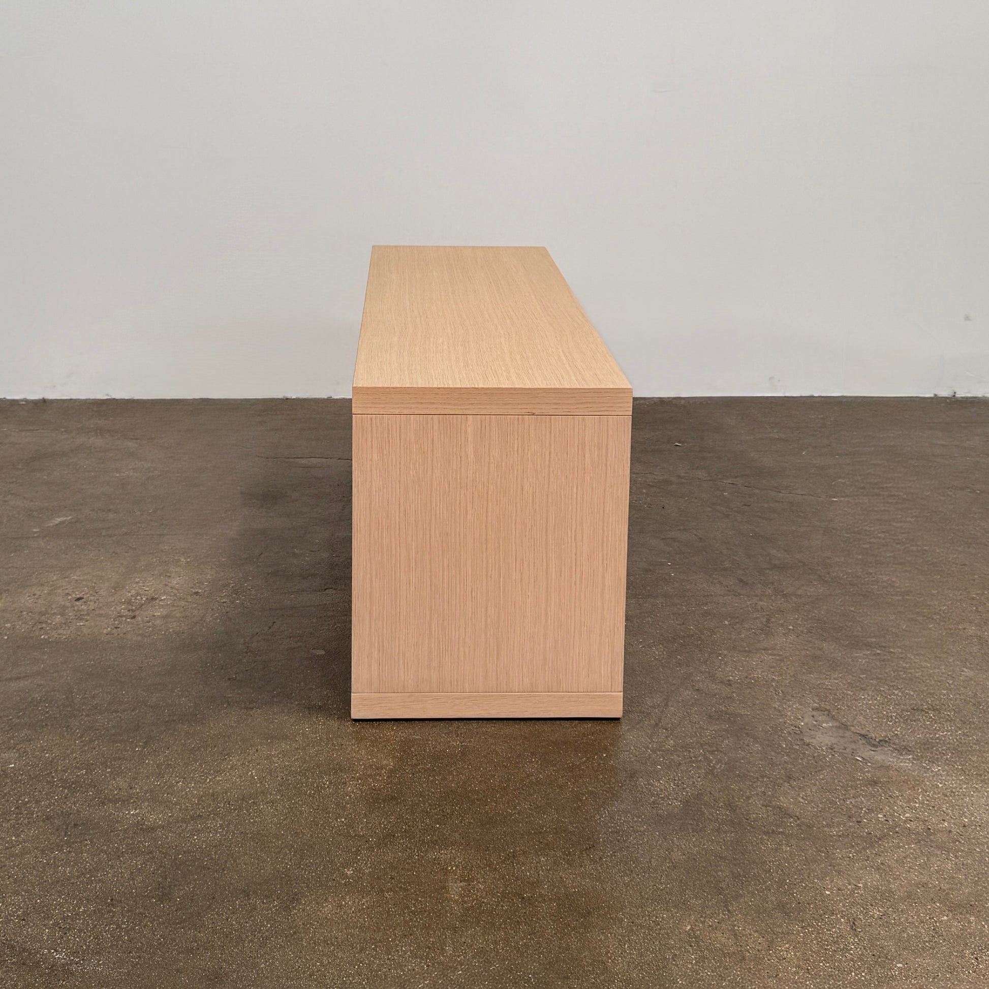 The B&B Italia Frank Low Console by B&B Italia rests on a polished concrete floor against a plain white wall.
