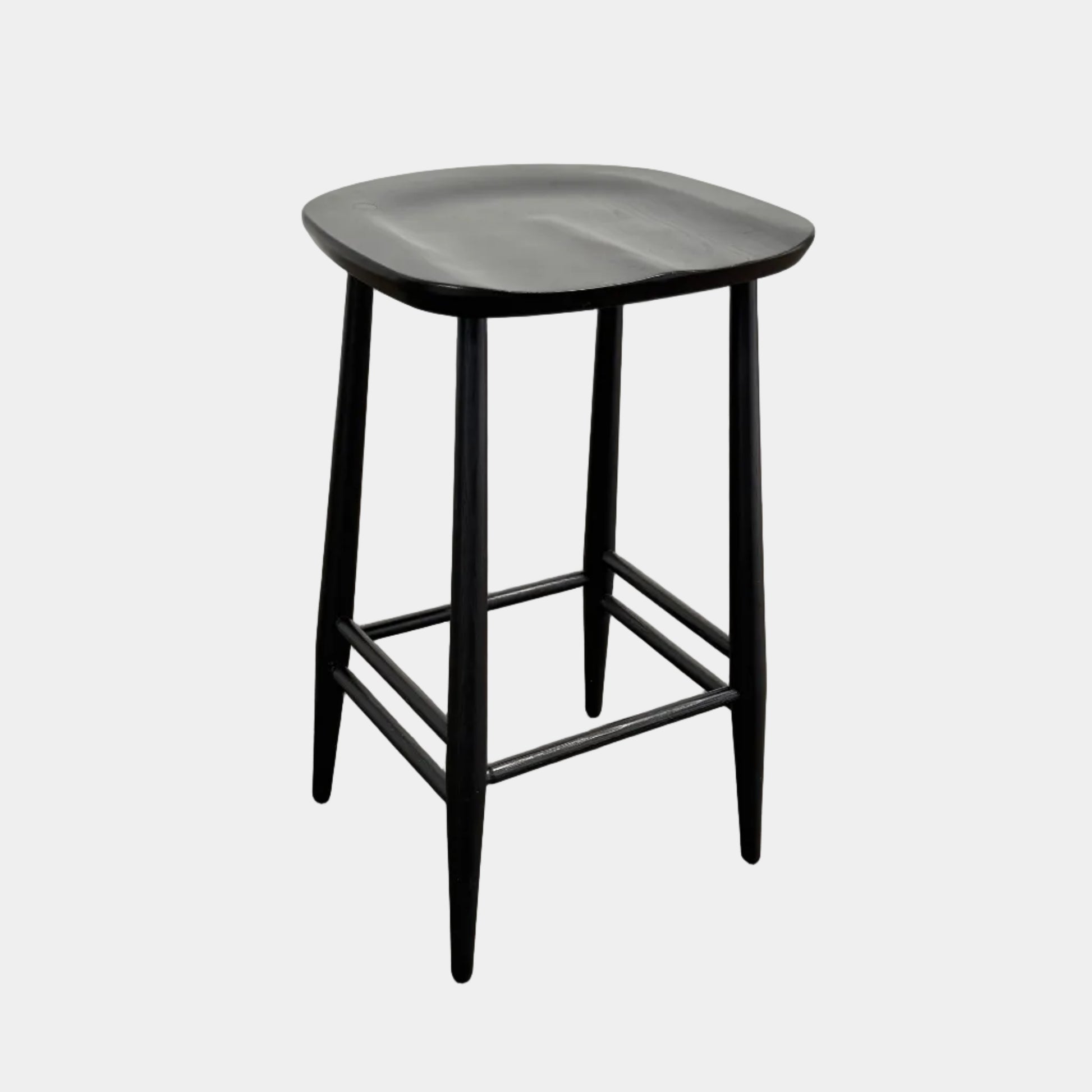 The Ercol Originals Counter Stool in Black Ash, crafted by Ercol, features four legs, a square contoured seat, and footrests on two sides. Set against a plain white background, this piece showcases the timeless craftsmanship of handmade British furniture.