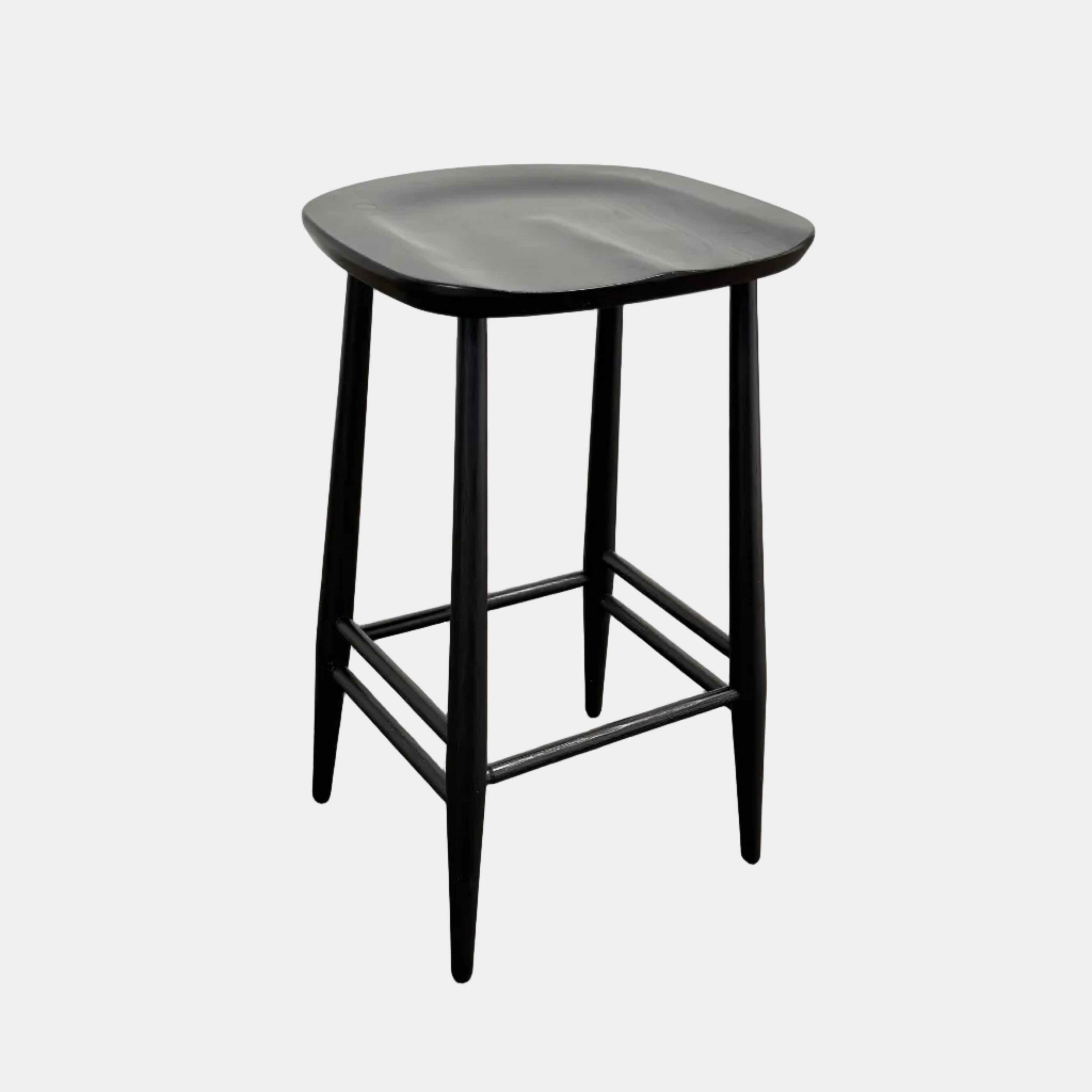 The Ercol Originals Counter Stool in Black Ash, crafted by Ercol, features four legs, a square contoured seat, and footrests on two sides. Set against a plain white background, this piece showcases the timeless craftsmanship of handmade British furniture.