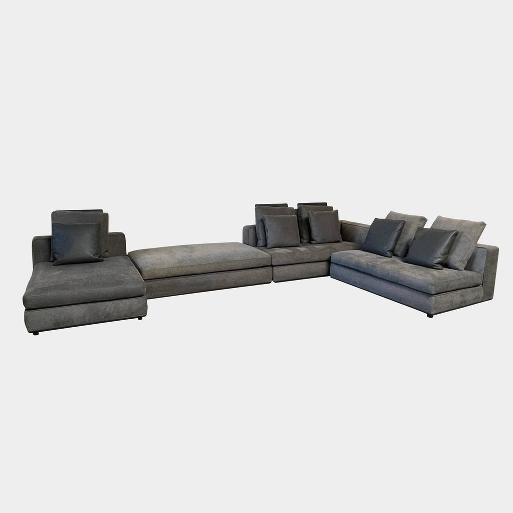 A Minotti Powell Sectional Sofa with black pillows from Minotti.