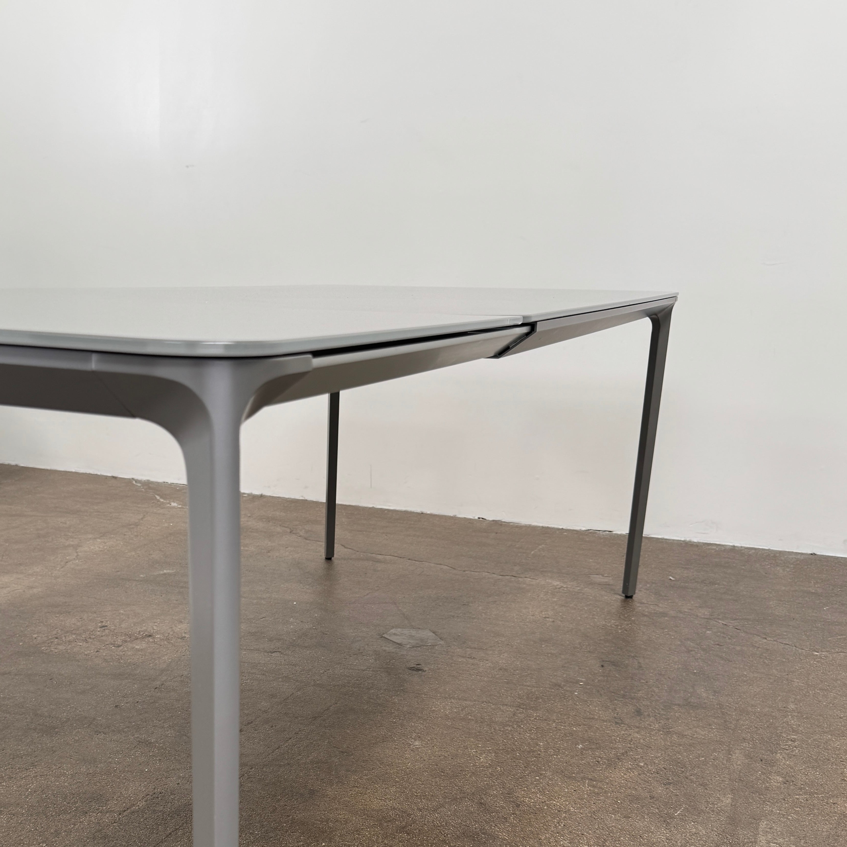 A minimalist rectangular Sovet Slim Extendable Dining Table in gray with four straight legs, designed by Sovet and photographed against a white background.