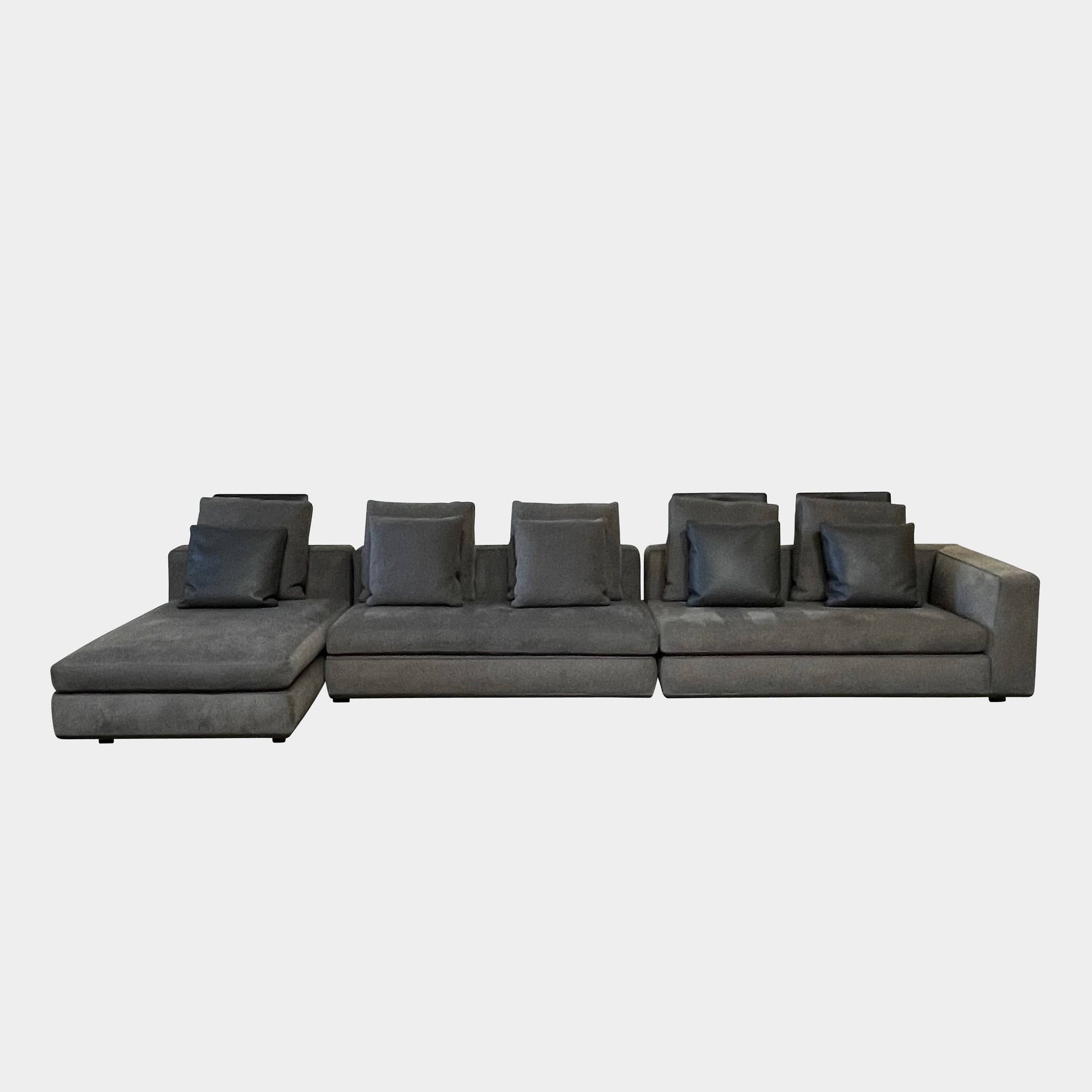 A Minotti Powell Sectional Sofa with black pillows from Minotti.