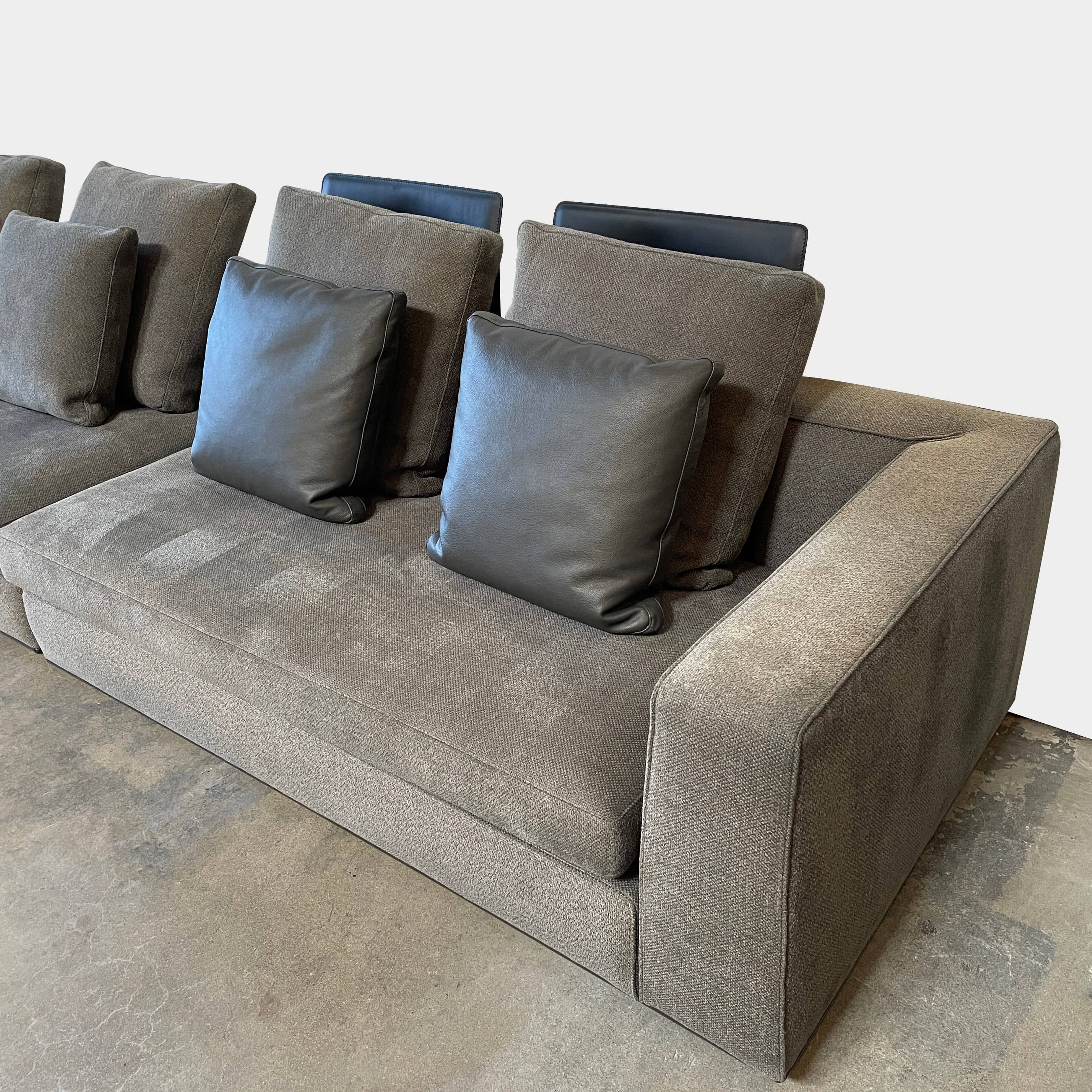 A Minotti Powell Sectional Sofa with black pillows from Minotti.