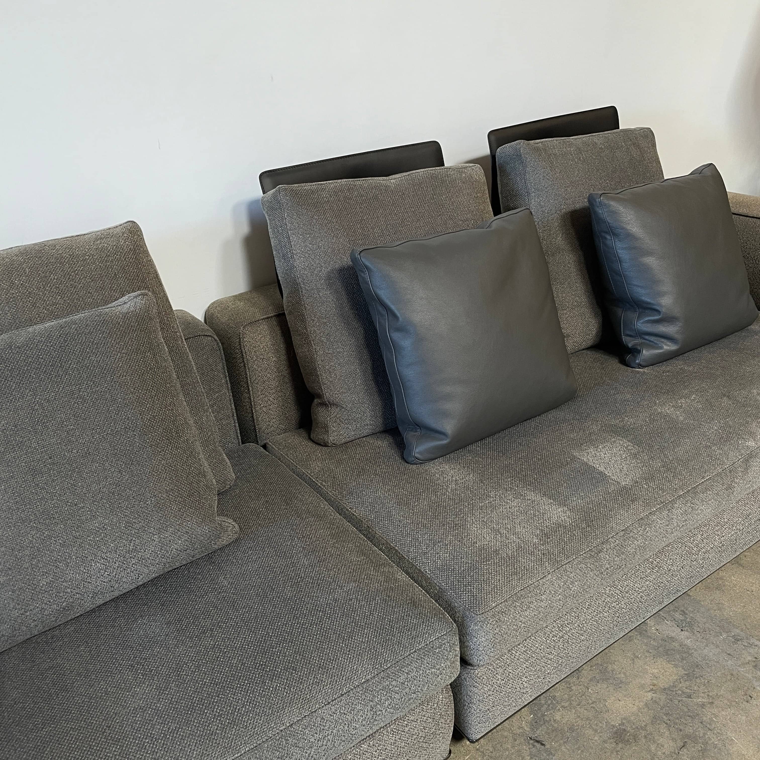 A Minotti Powell Sectional Sofa with black pillows from Minotti.