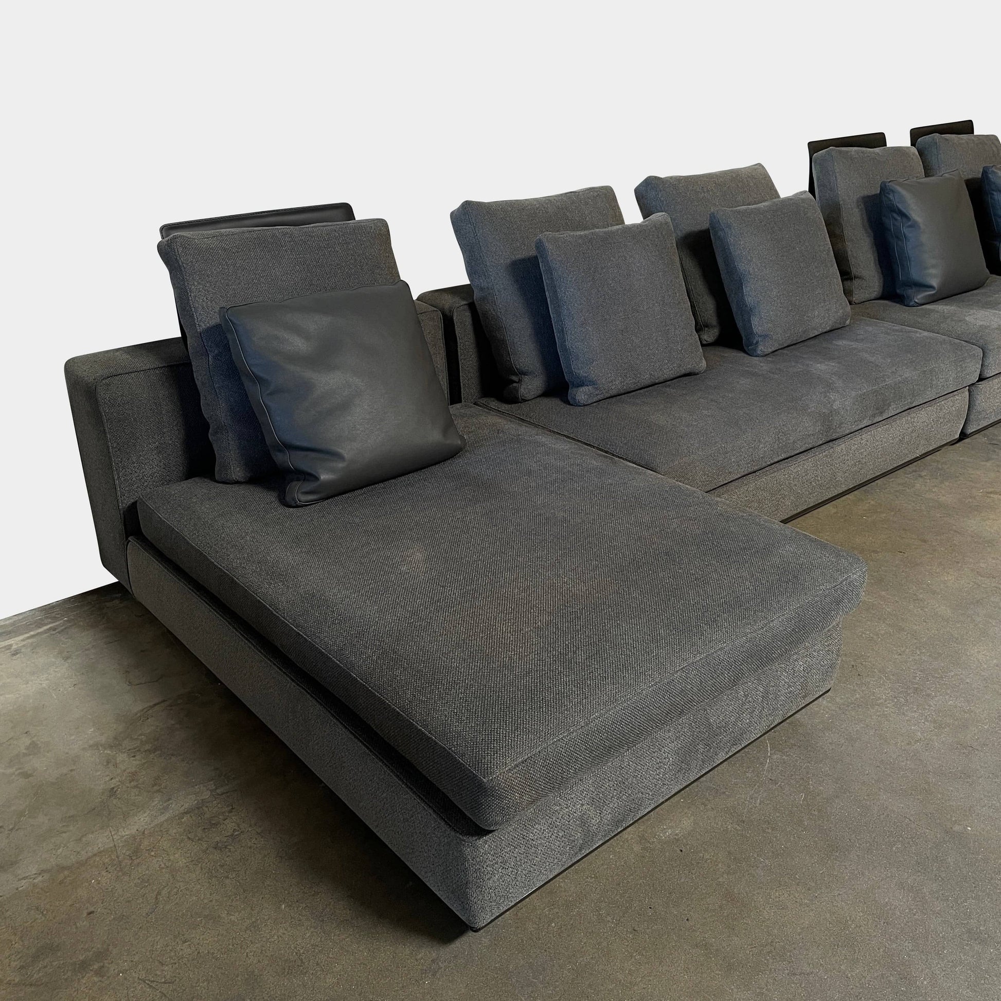 A Minotti Powell Sectional Sofa with black pillows from Minotti.