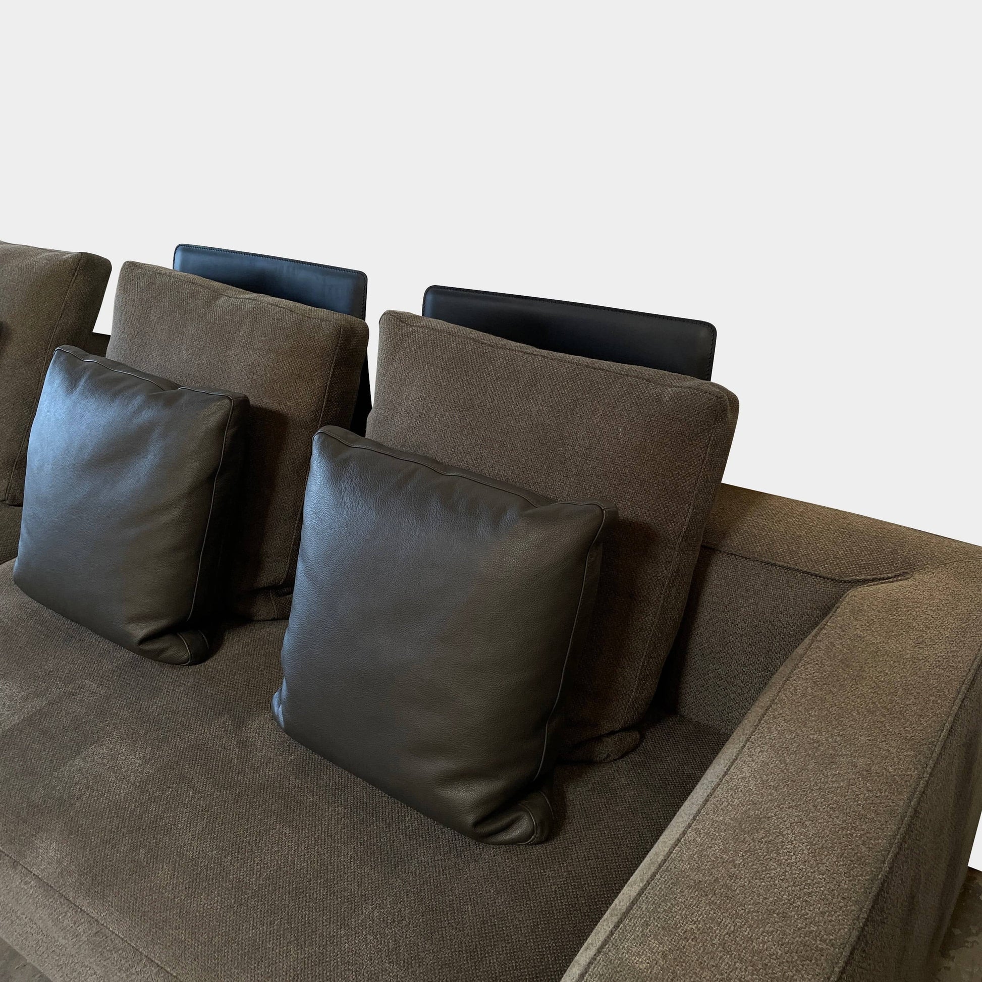 A Minotti Powell Sectional Sofa with black pillows from Minotti.