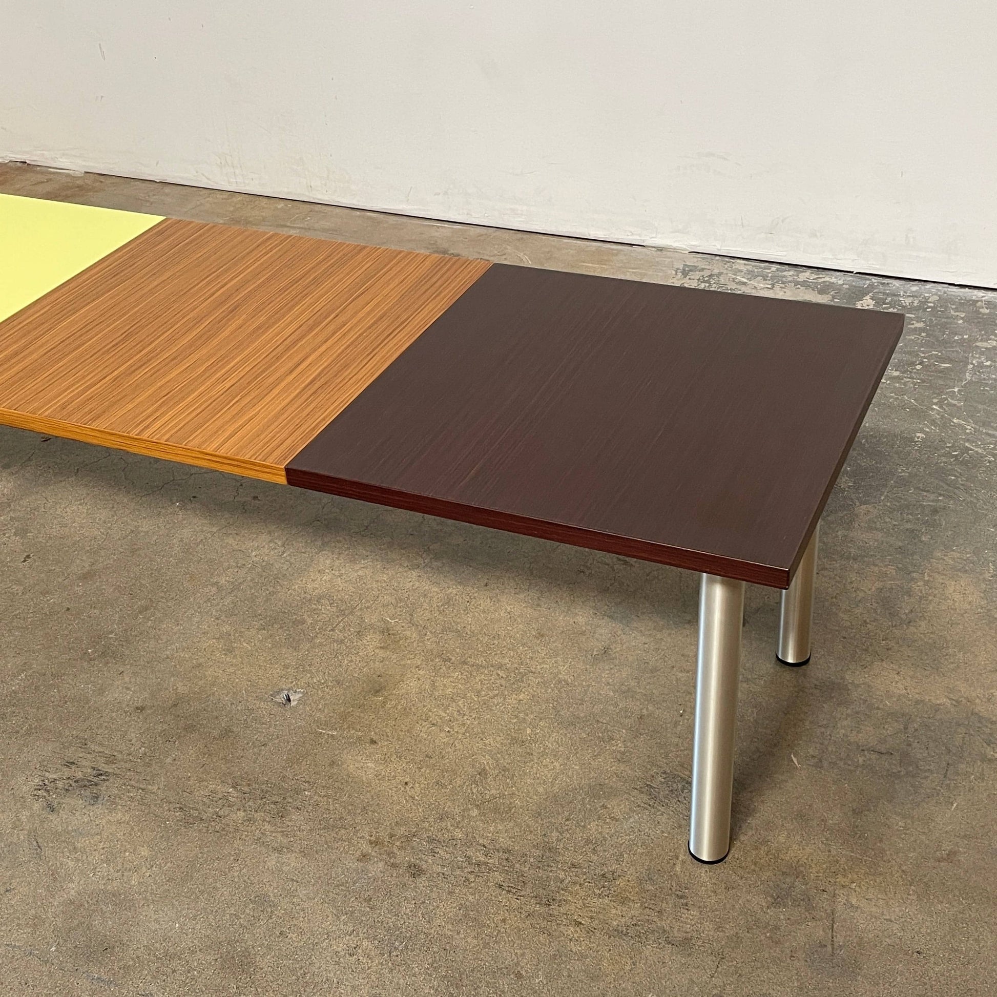 The Mazzei Multi-Panel Table by Mazzei is a contemporary design featuring a bench with a vibrant yellow, green, and blue top that adds functionality to any space.