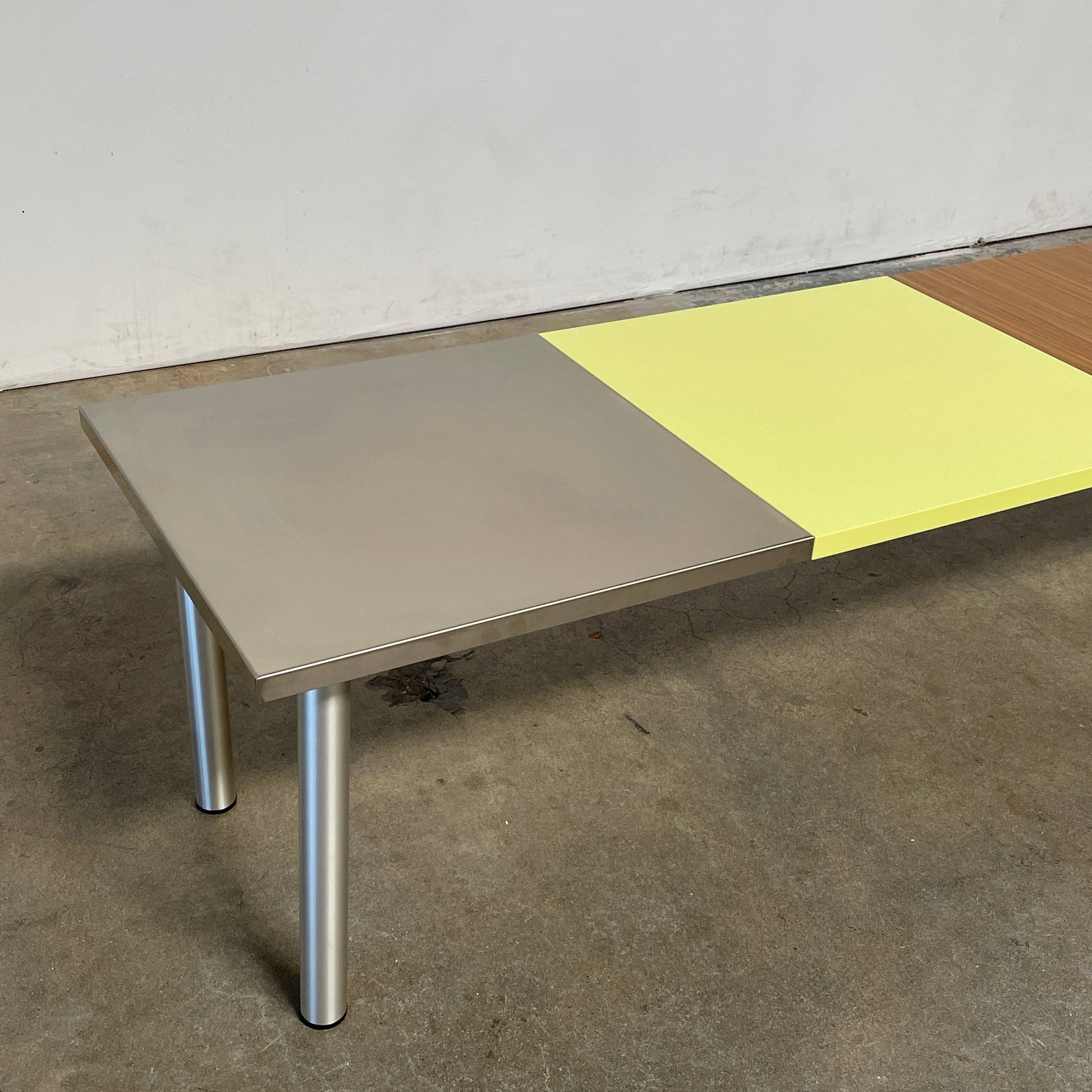 The Mazzei Multi-Panel Table by Mazzei is a contemporary design featuring a bench with a vibrant yellow, green, and blue top that adds functionality to any space.