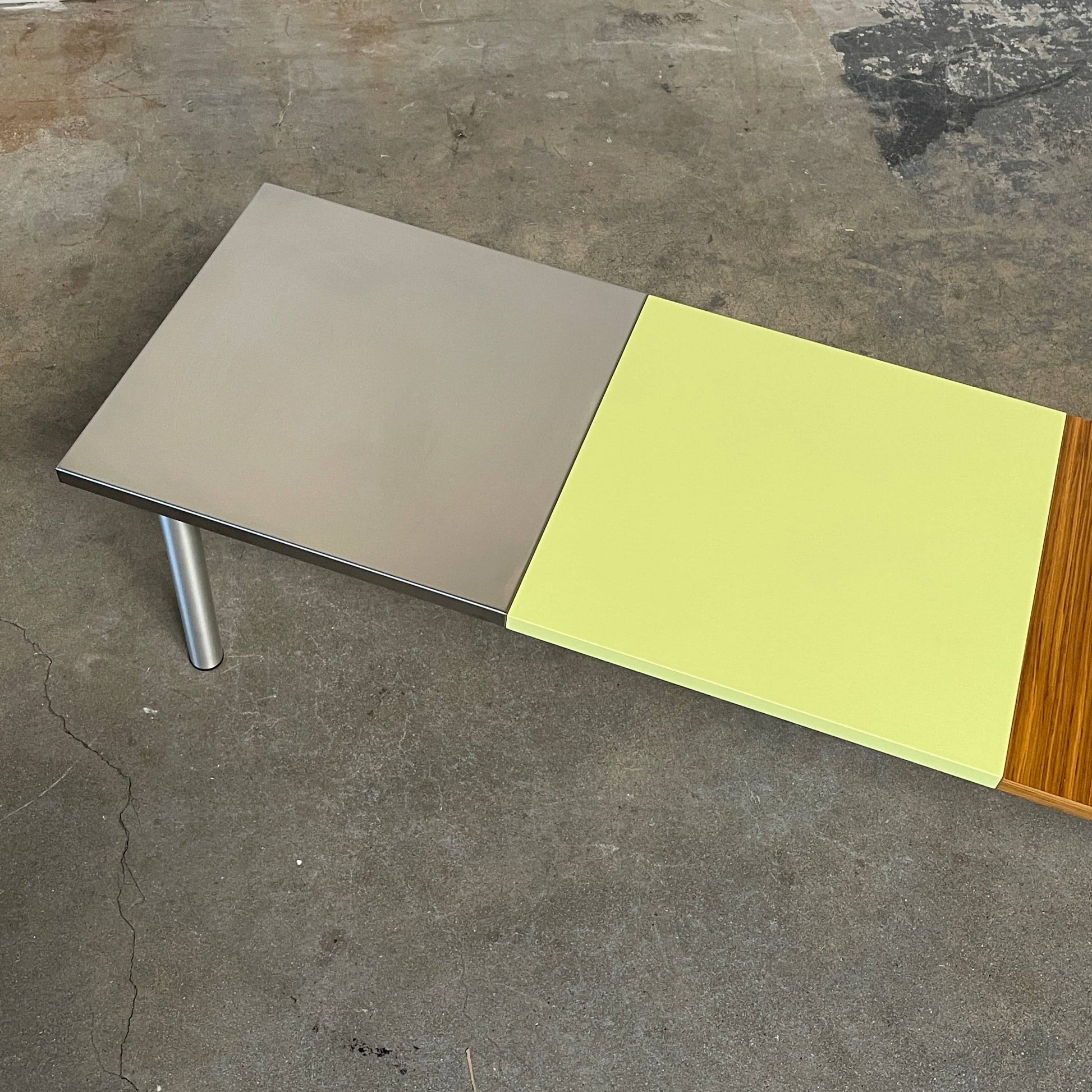 The Mazzei Multi-Panel Table by Mazzei is a contemporary design featuring a bench with a vibrant yellow, green, and blue top that adds functionality to any space.