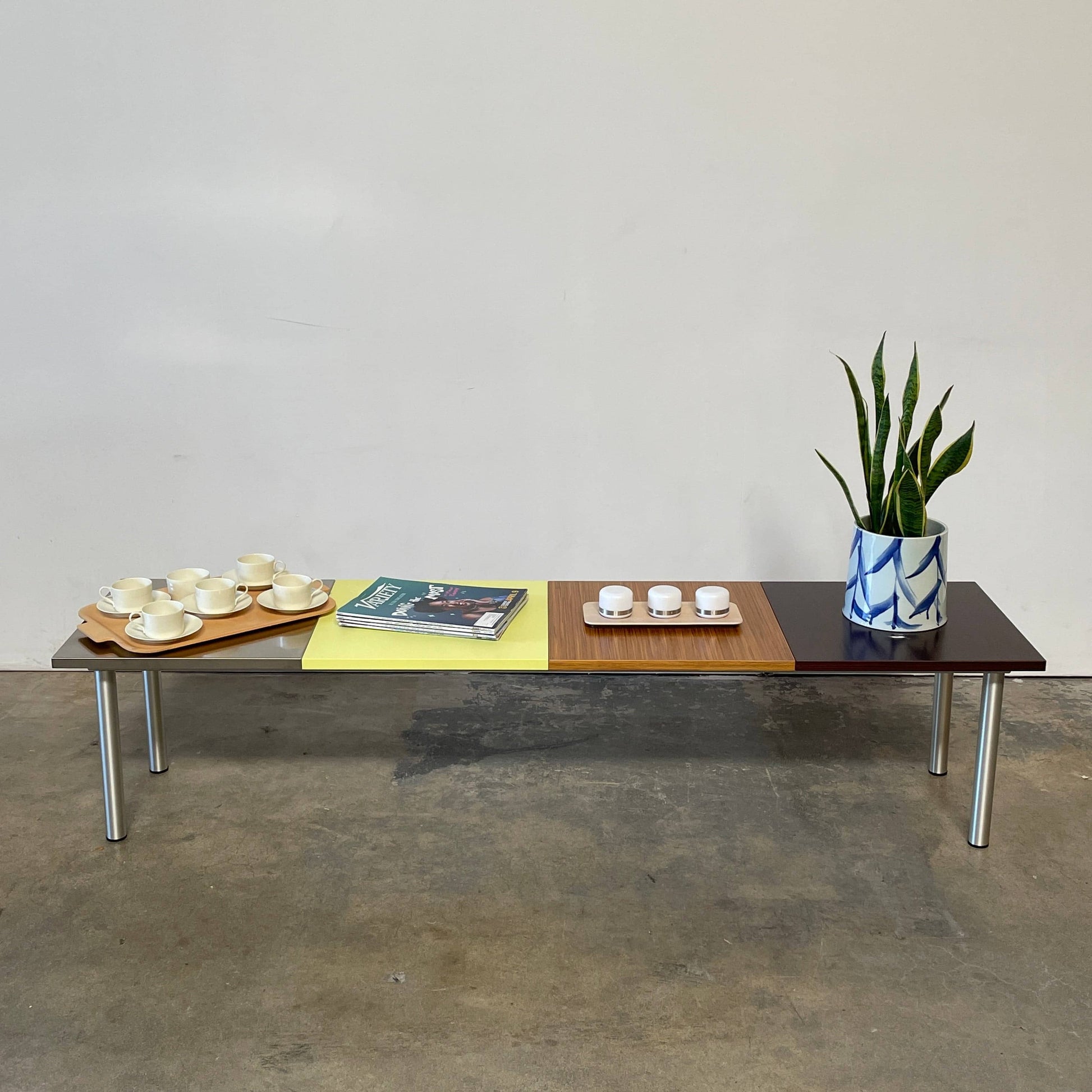The Mazzei Multi-Panel Table by Mazzei is a contemporary design featuring a bench with a vibrant yellow, green, and blue top that adds functionality to any space.